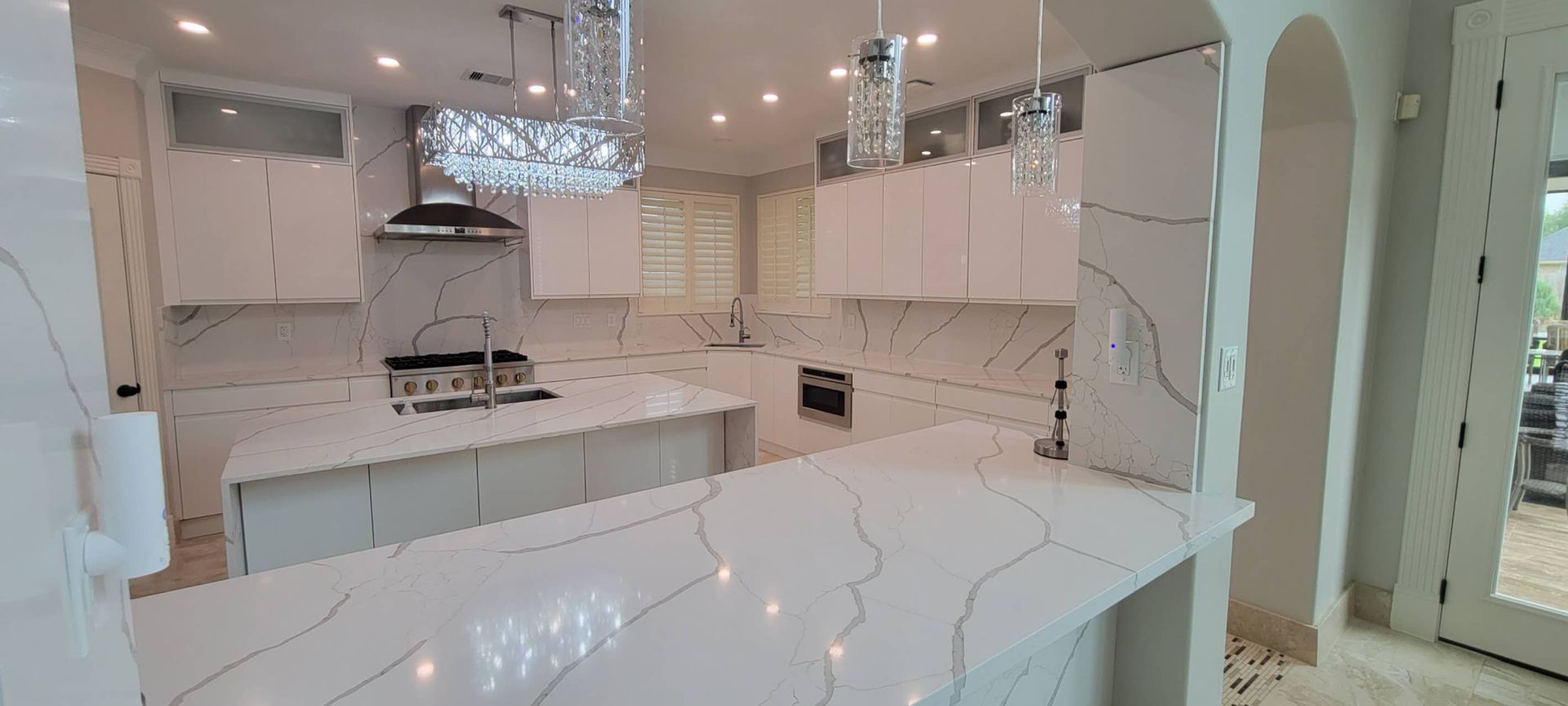 A kitchen with white cabinets , white counter tops , and a large island.