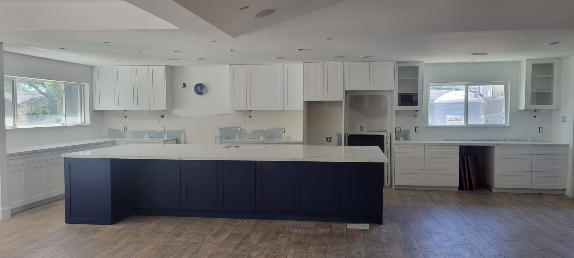 A kitchen with white cabinets and a large island in the middle.