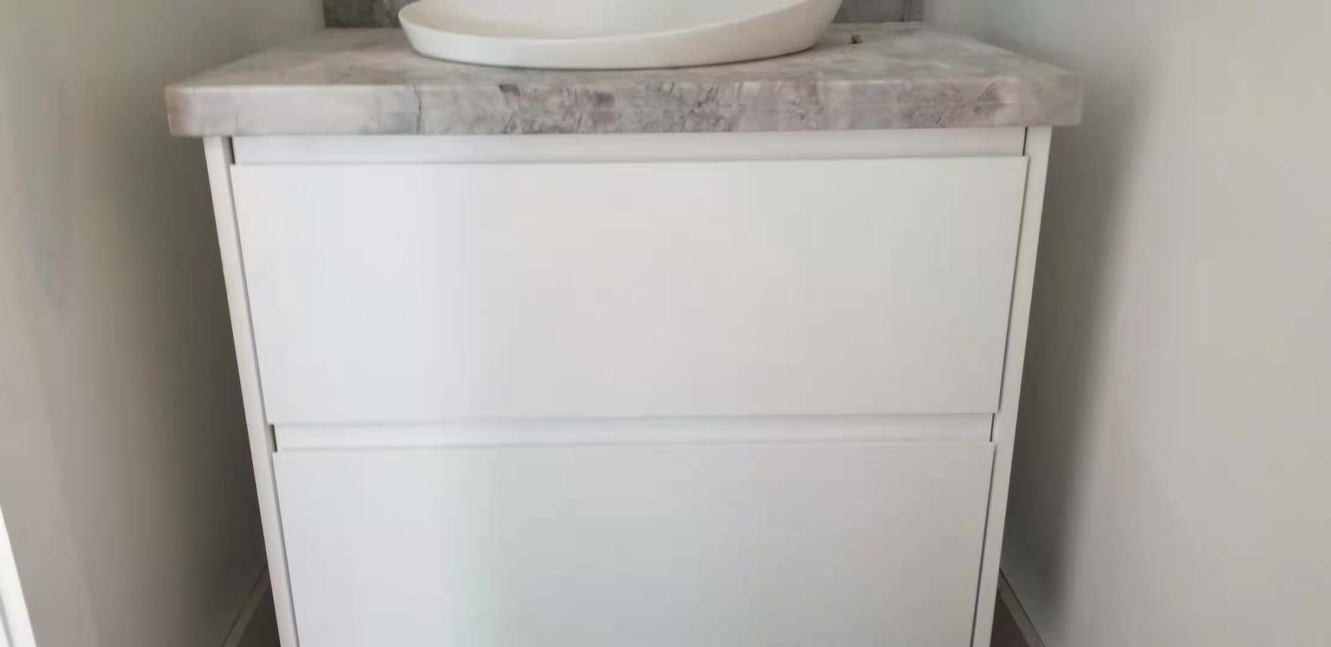 A white vanity with a sink on top of it in a bathroom.