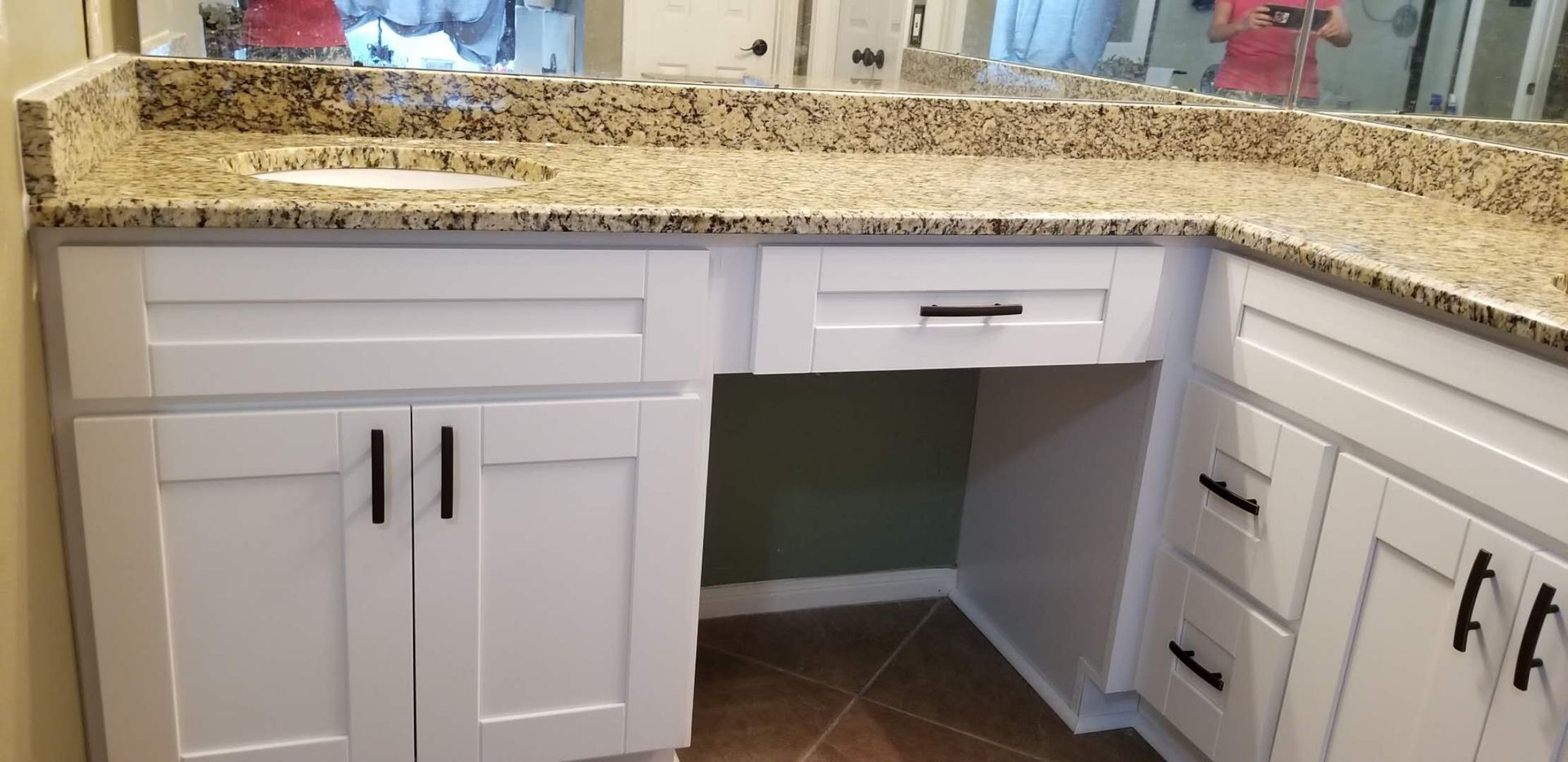 A bathroom with white cabinets , granite counter tops , a sink and a mirror.