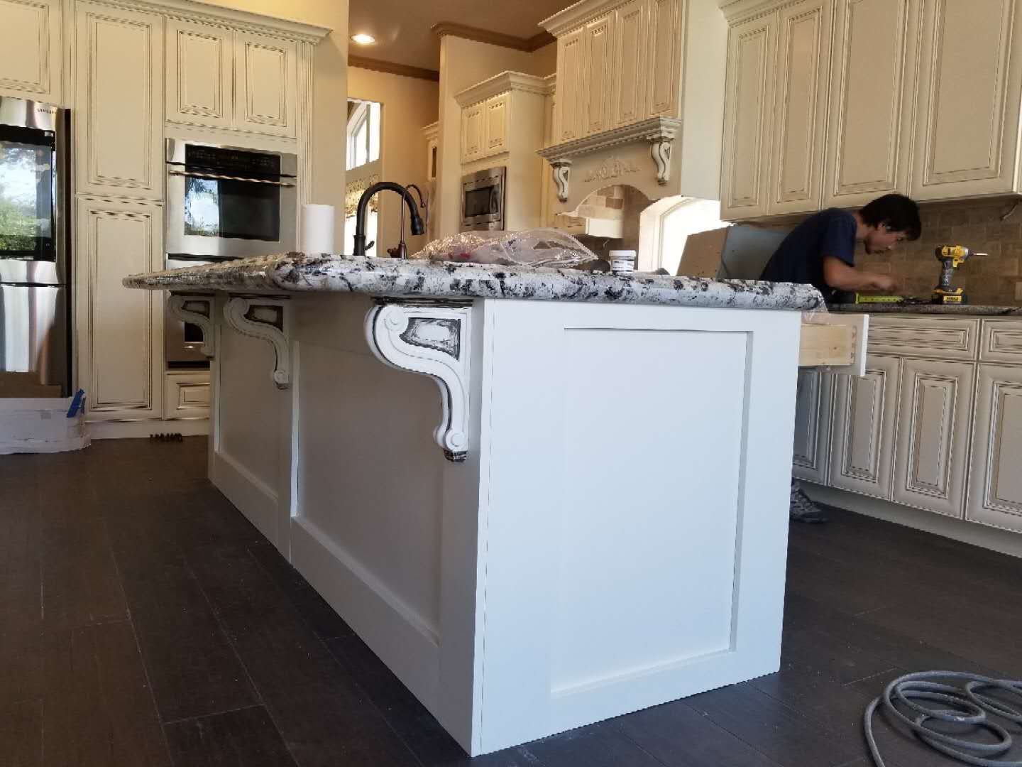 A man is working on a large island in a kitchen.