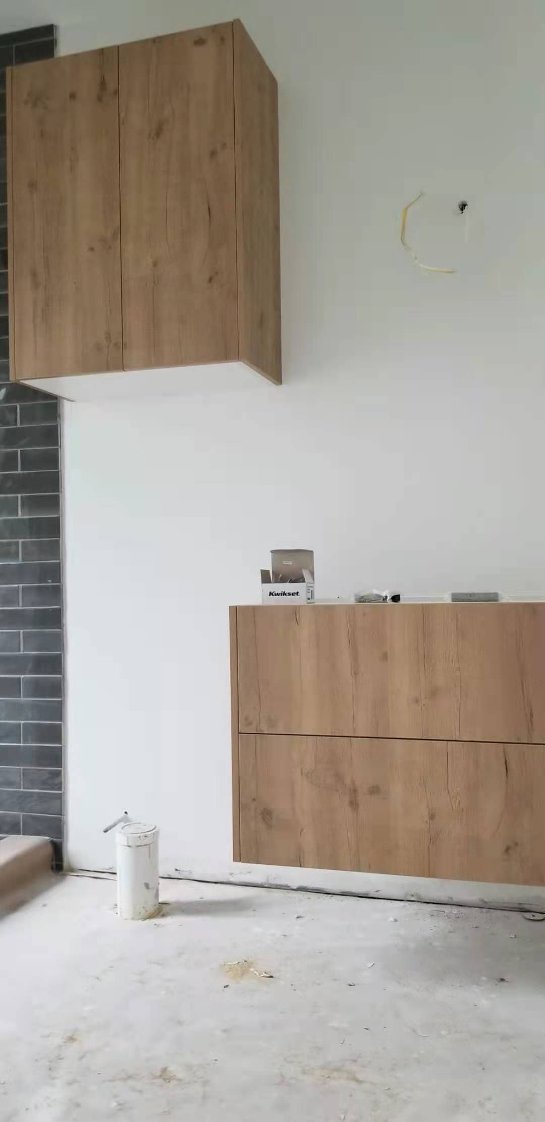 A room with wooden cabinets and a bucket on the floor.