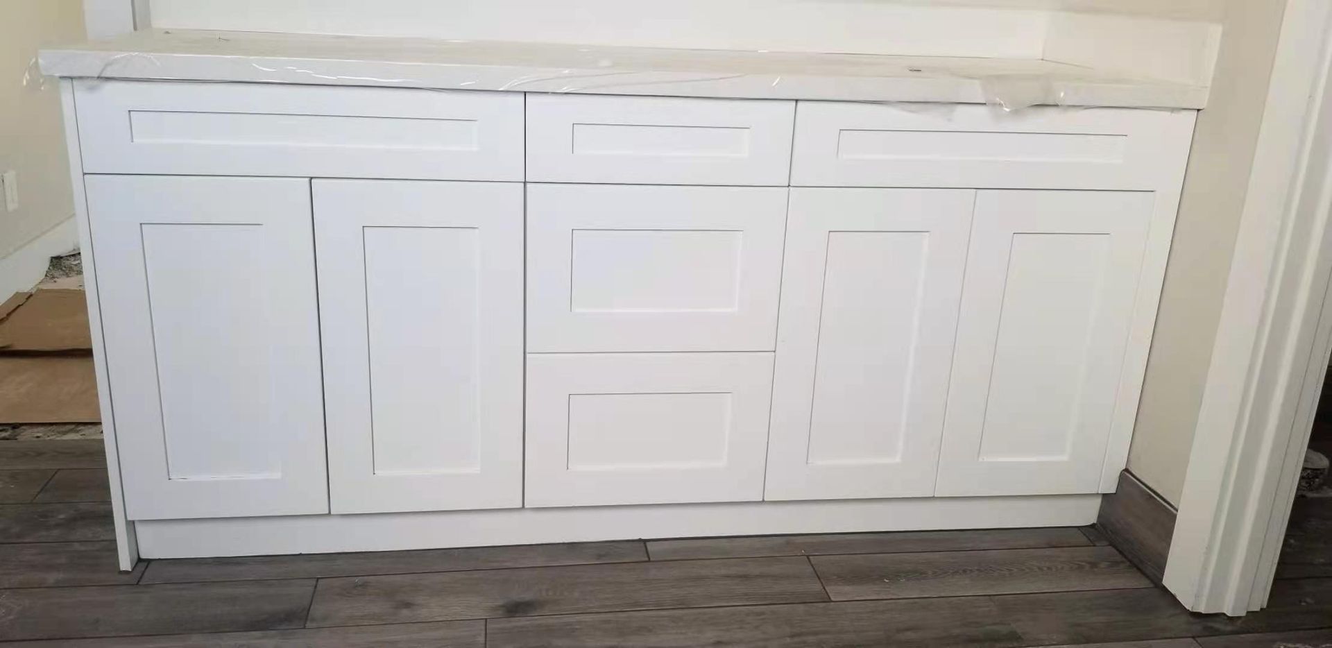 A bathroom vanity with white cabinets and drawers in a room.