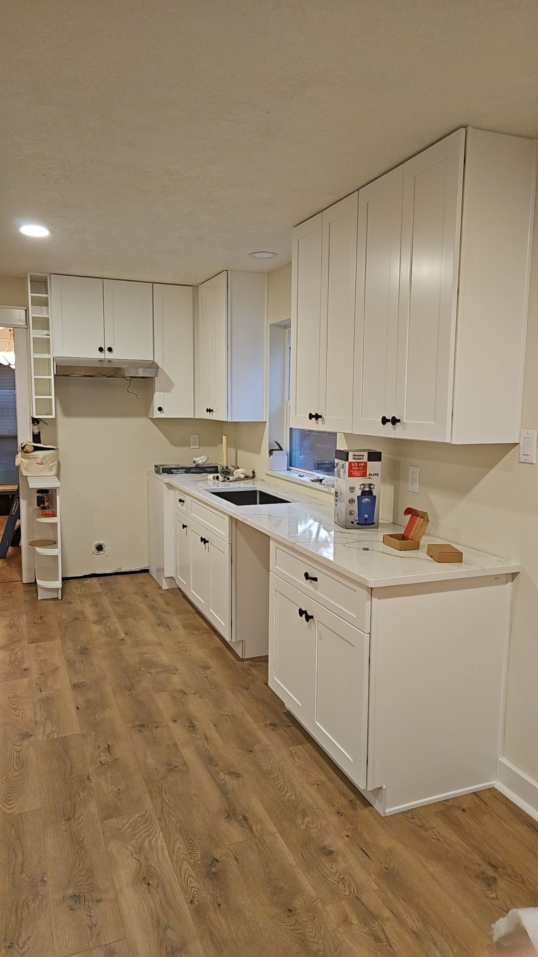 A kitchen with white cabinets and wooden floors.