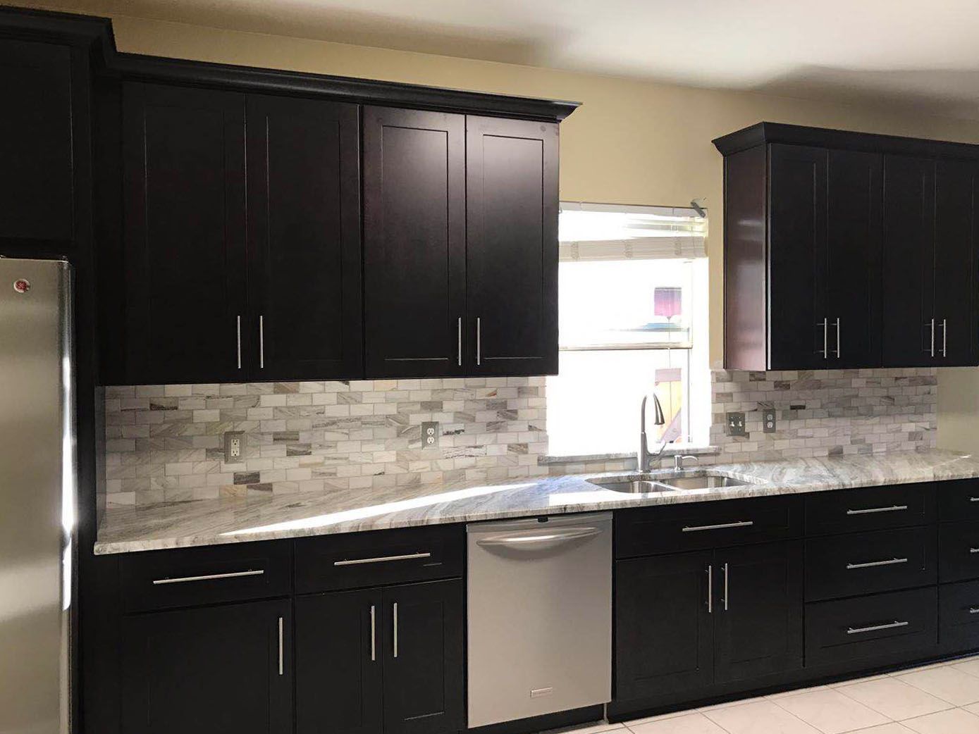 A kitchen with black cabinets and stainless steel appliances