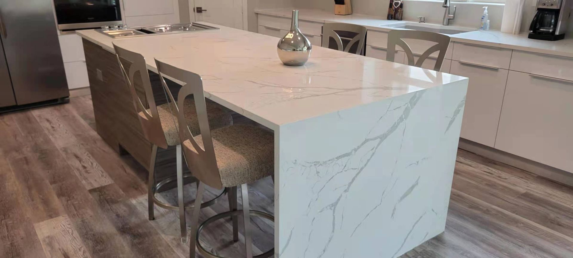 There is a large island in the middle of the kitchen with stools.