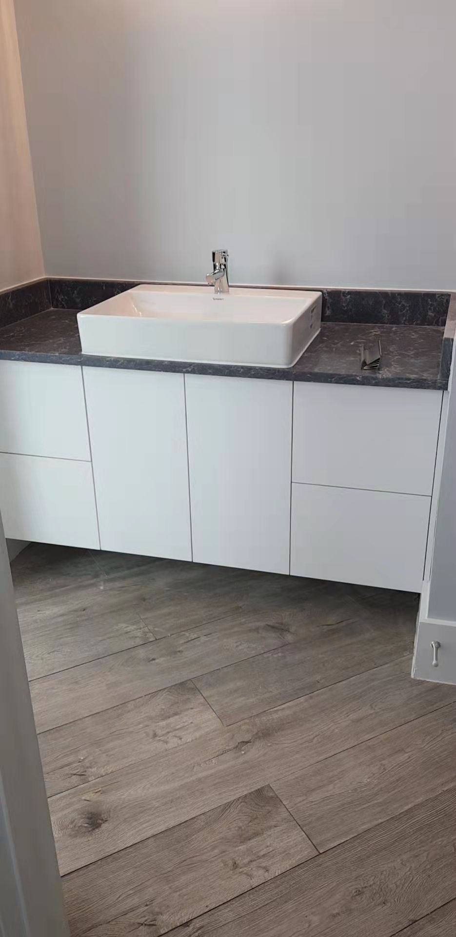 A bathroom with a sink and a wooden floor.