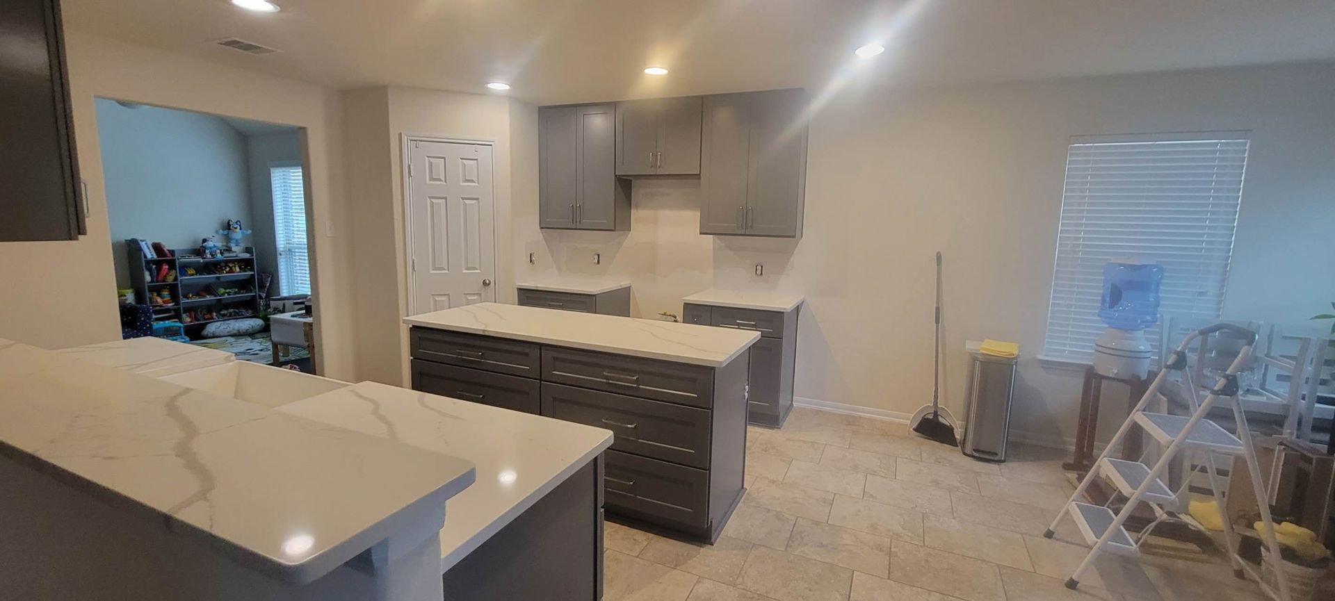 A kitchen with gray cabinets and white counter tops is being remodeled.