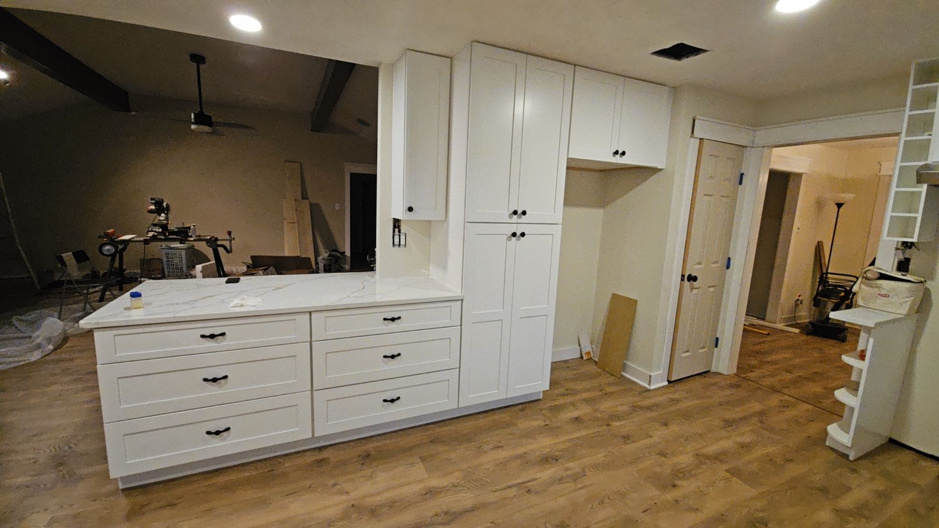 A kitchen with white cabinets and wooden floors is being remodeled.