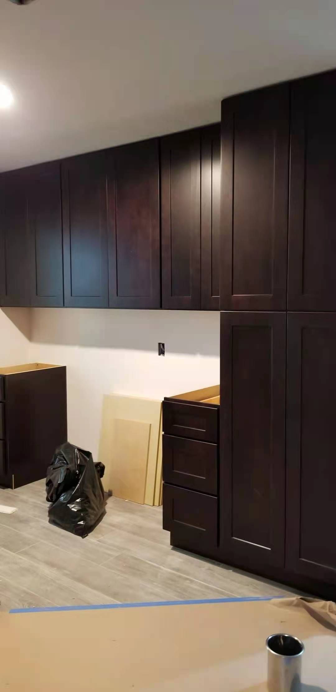 A kitchen with dark wooden cabinets and drawers is being remodeled.