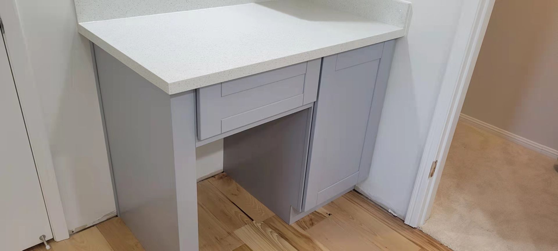 A small desk with a white top and drawers in a bathroom.