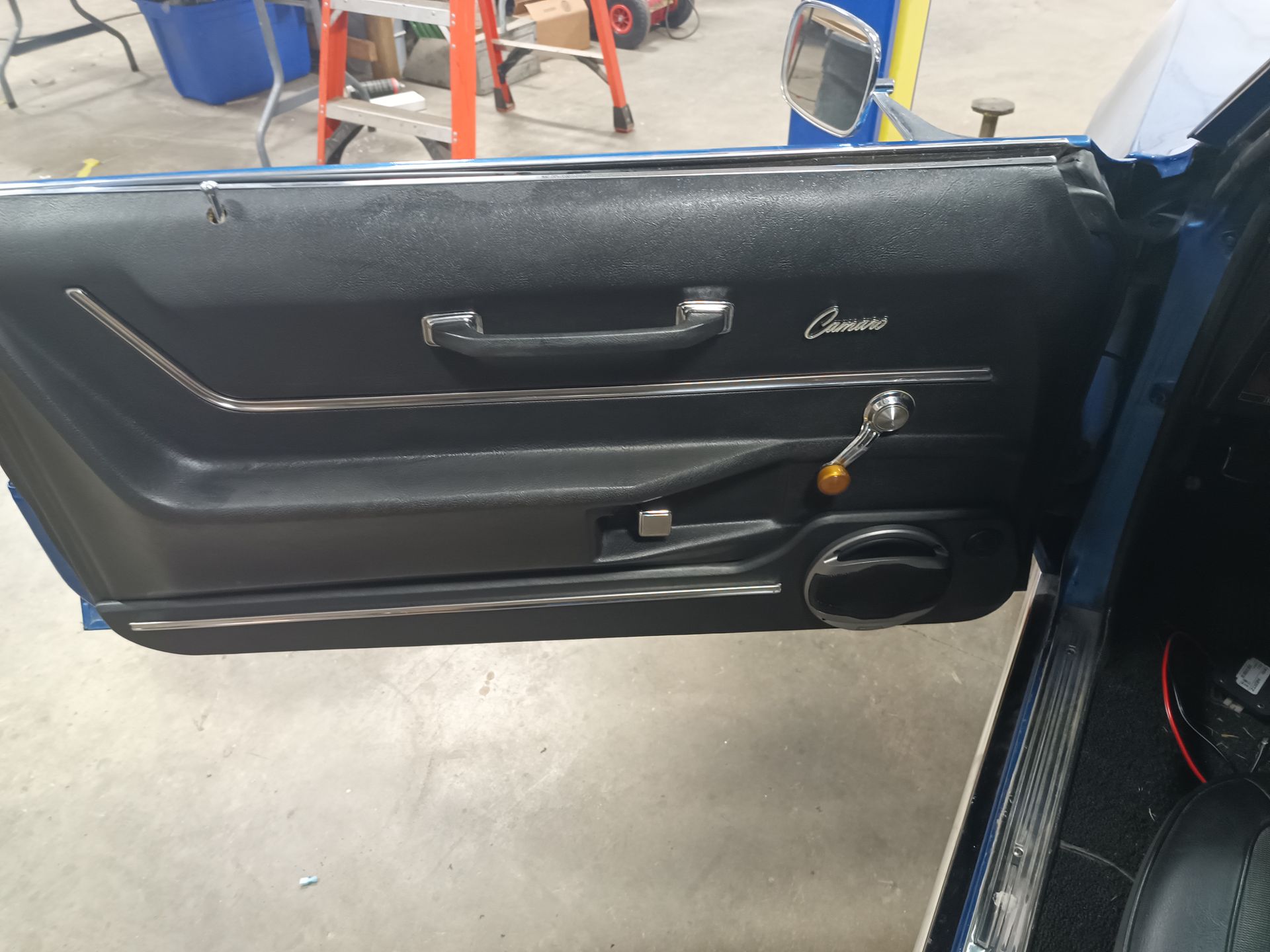 Black car door panel with chrome trim, handle, and a 
