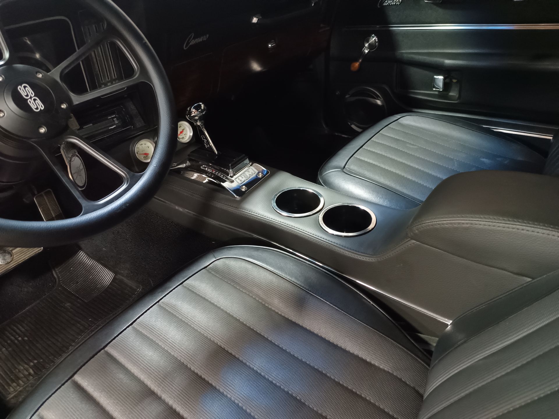 Black car interior with leather seats, cup holders, and a steering wheel.