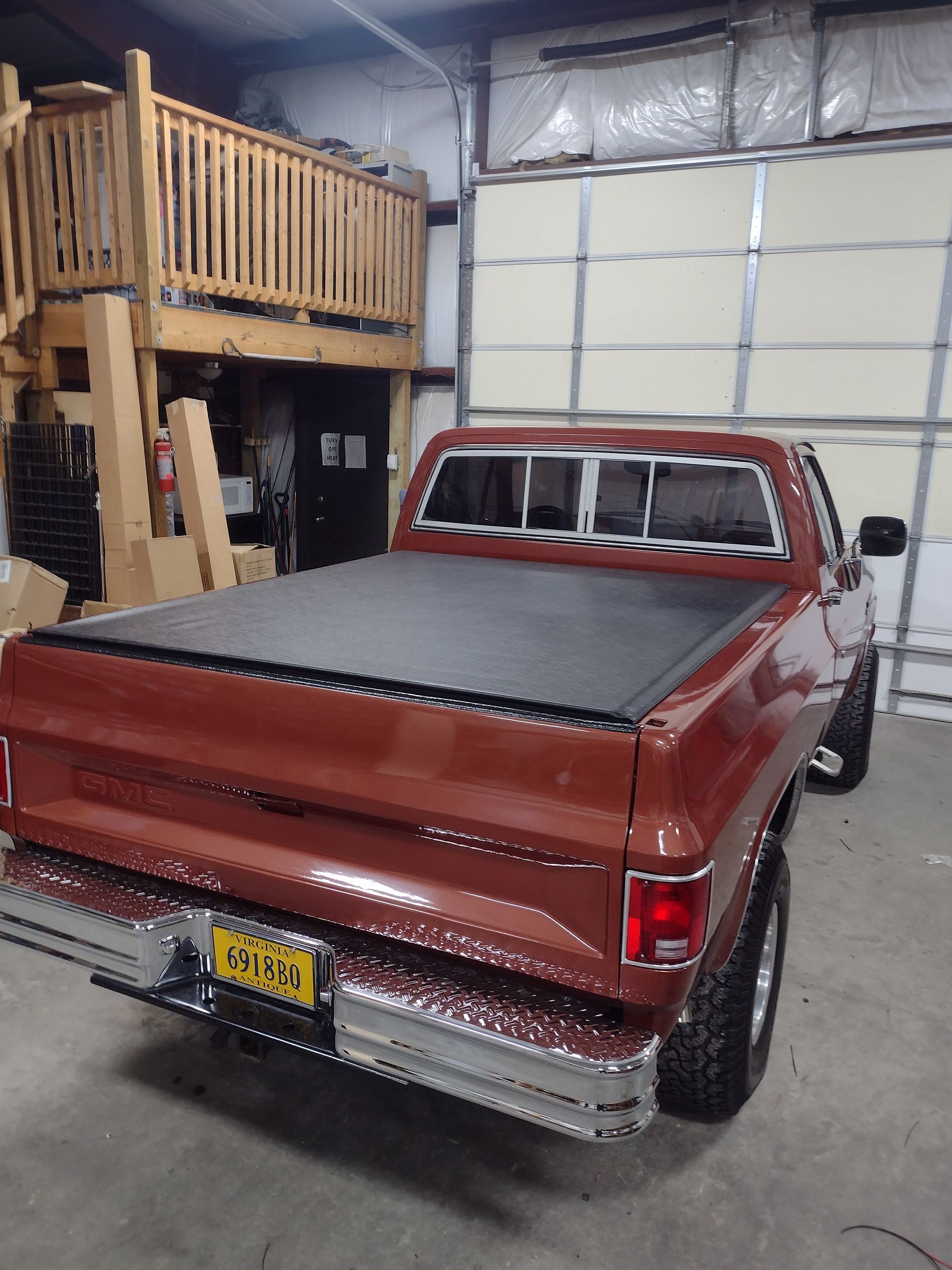 Brown Chevrolet pickup truck with a black tonneau cover, parked inside a garage.
