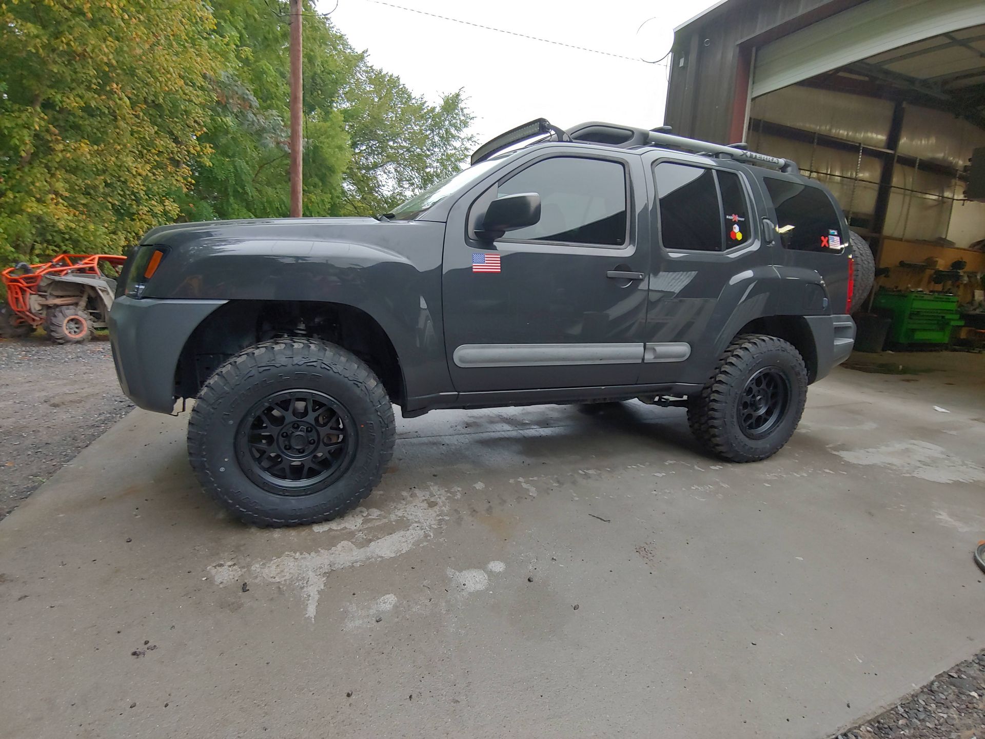 Dark gray off-road SUV with black wheels parked near a building.