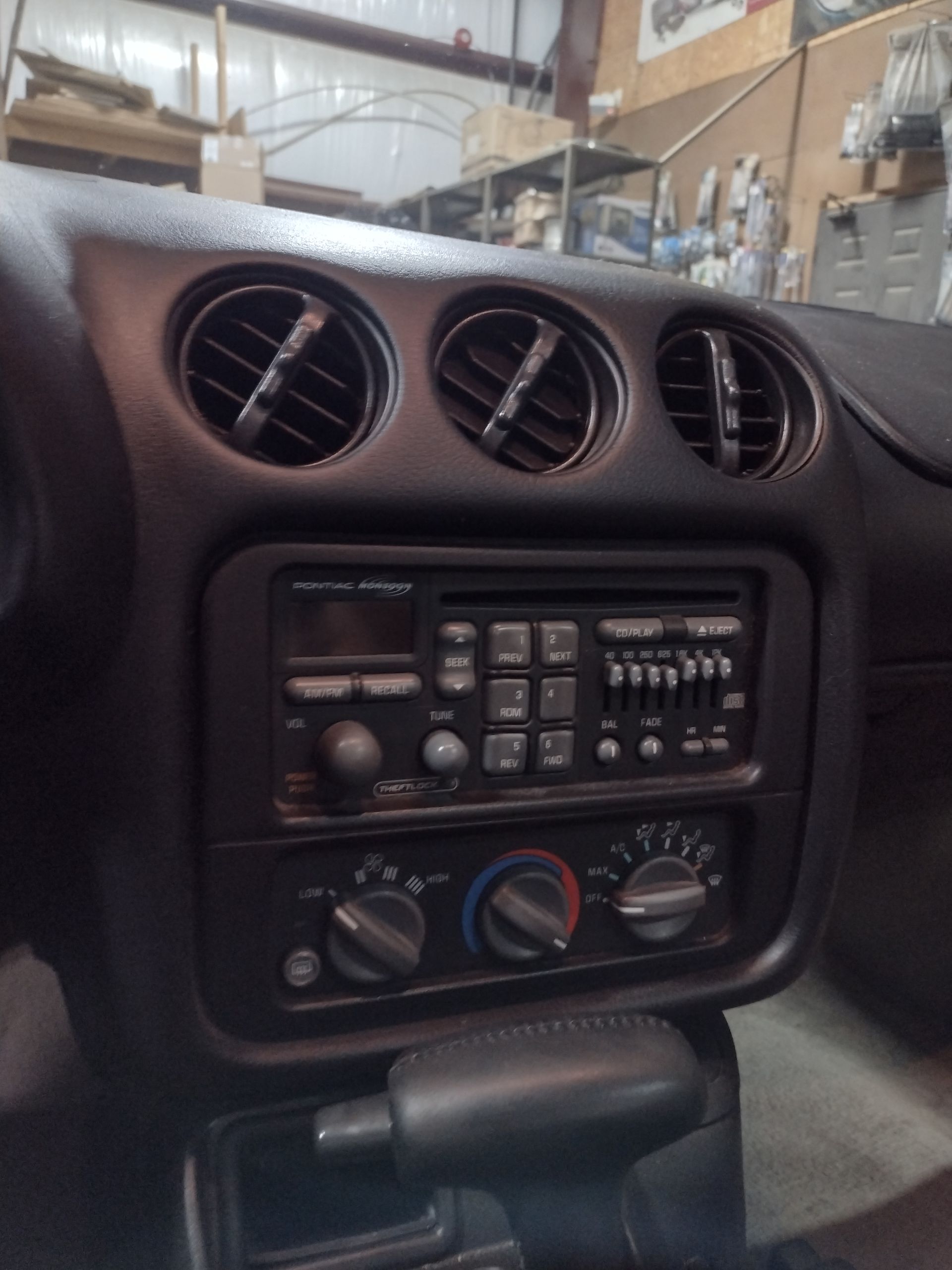 Car dashboard with air vents, stereo, and climate controls. Black interior.