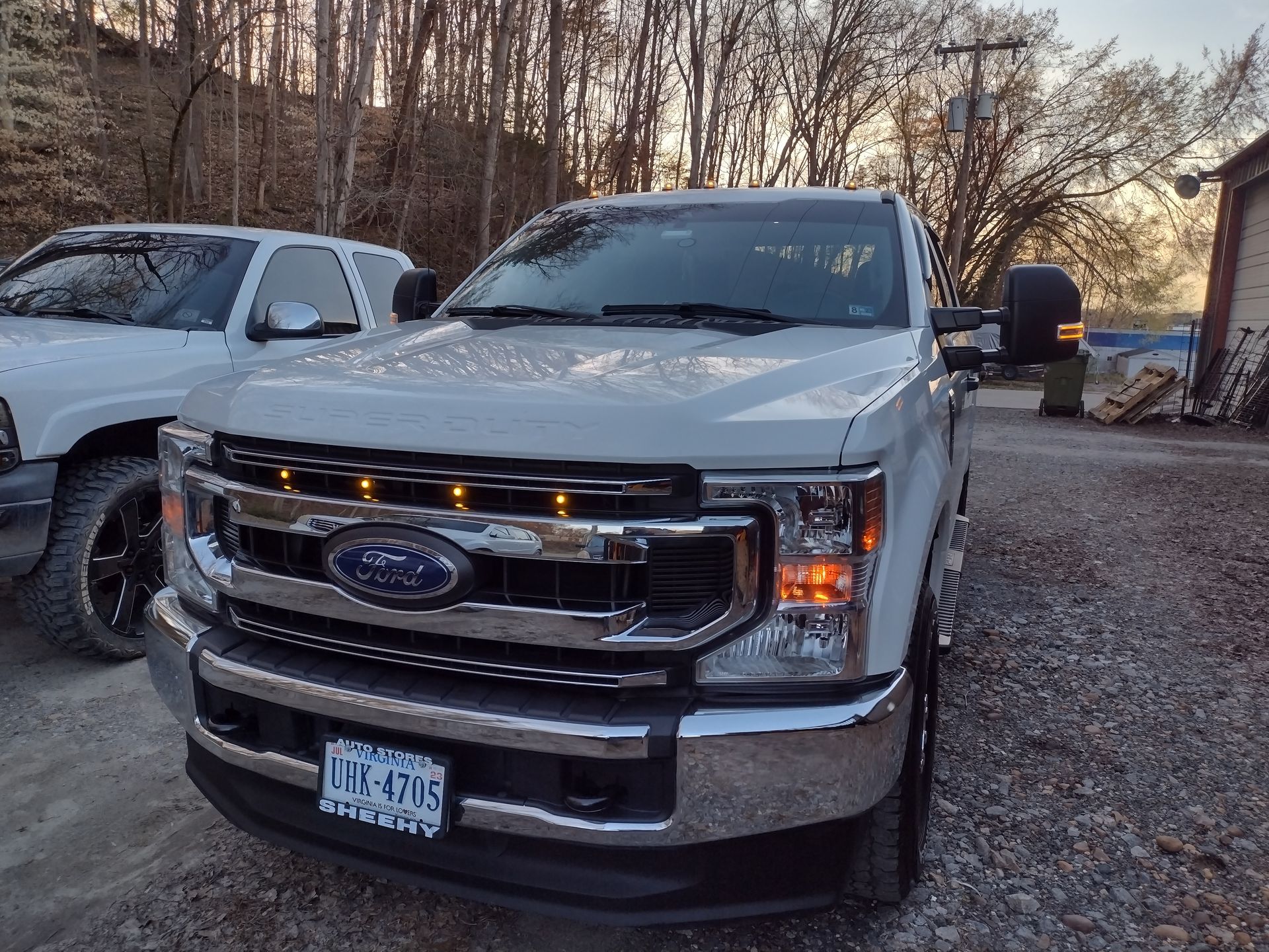 White Ford truck with amber lights parked outside.