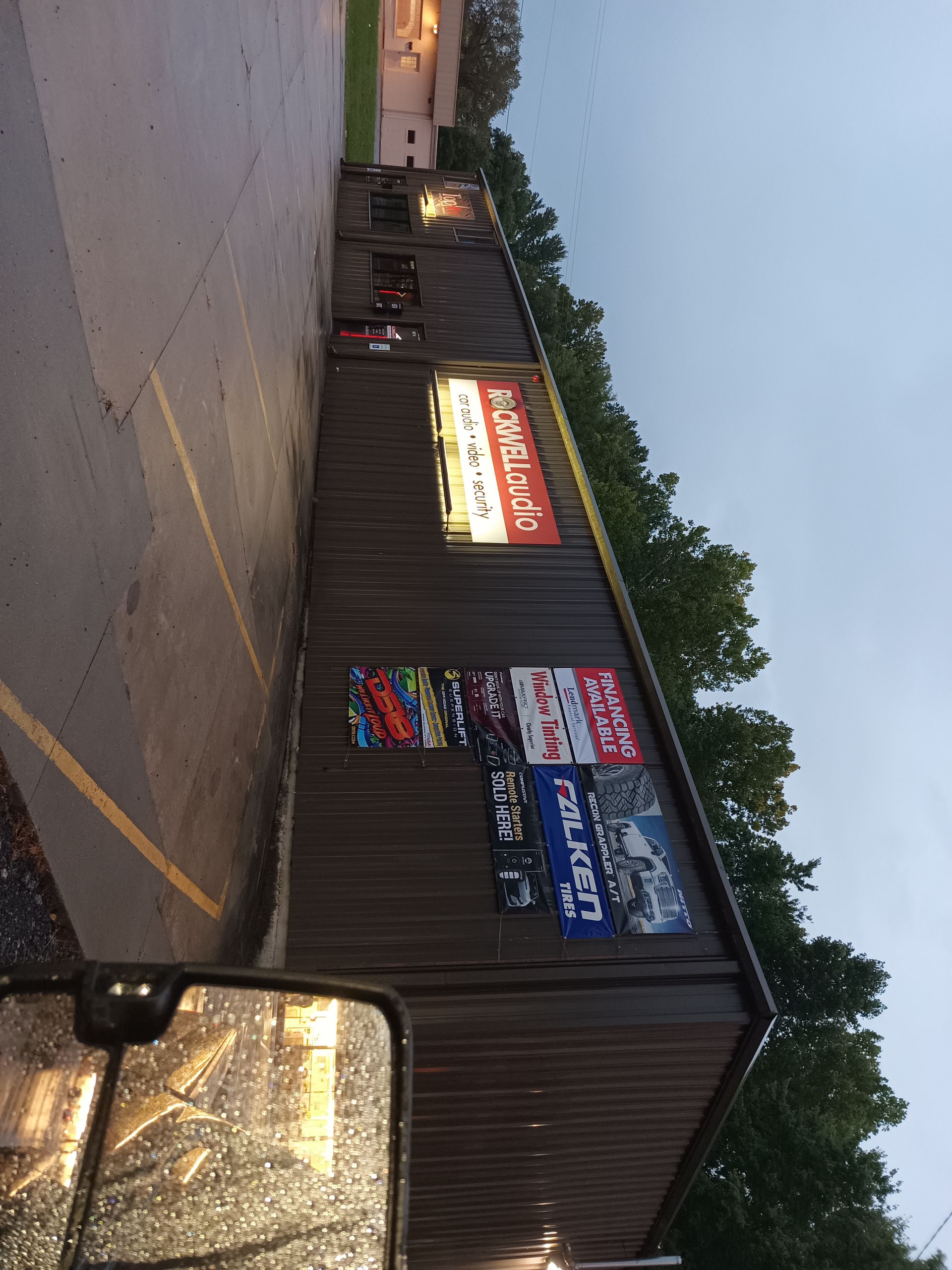 Exterior of a building with signs advertising products, likely a shop; overcast sky.