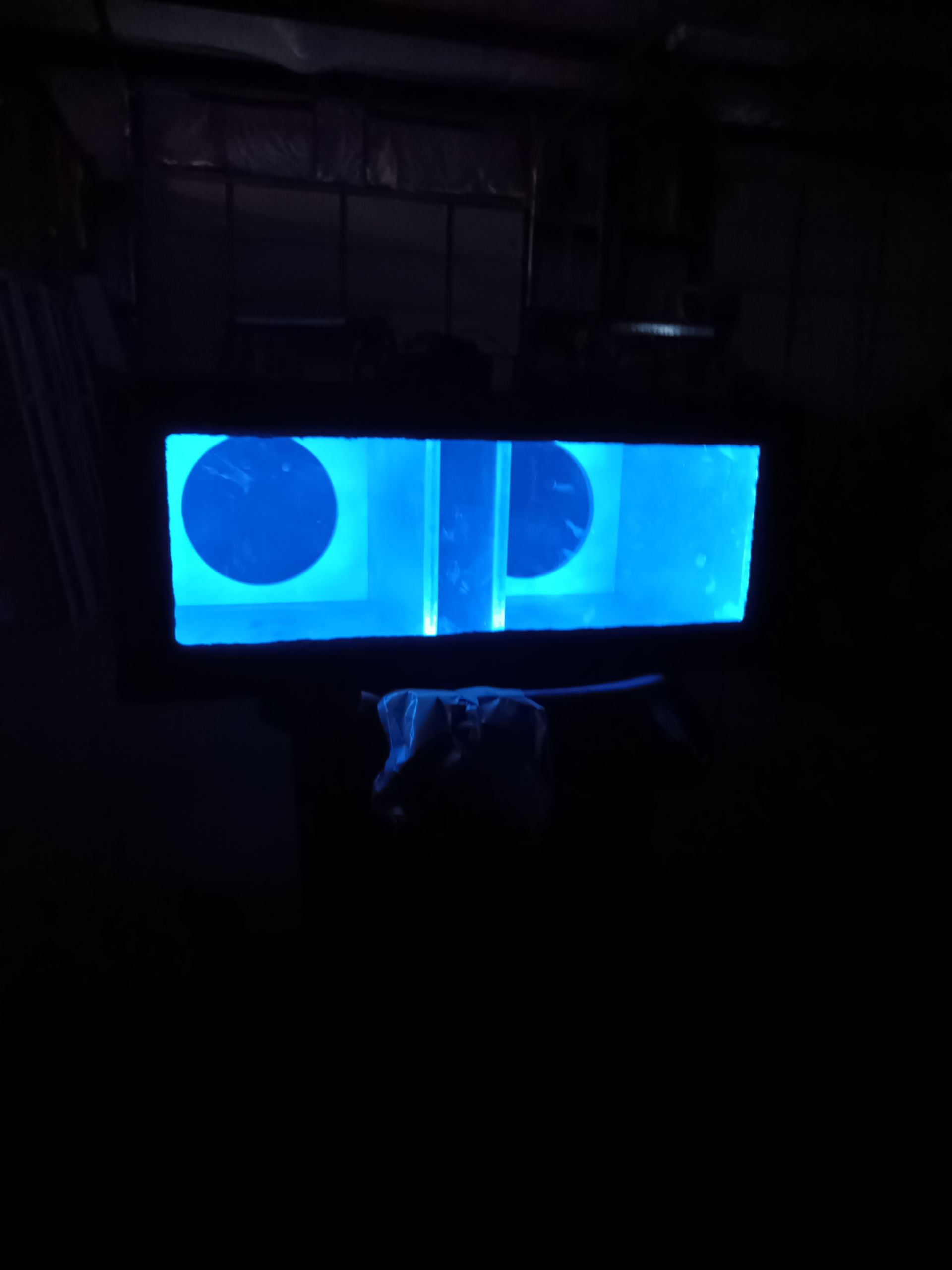 Blue-lit rectangular display with two circular features and a central bar in a dark environment.