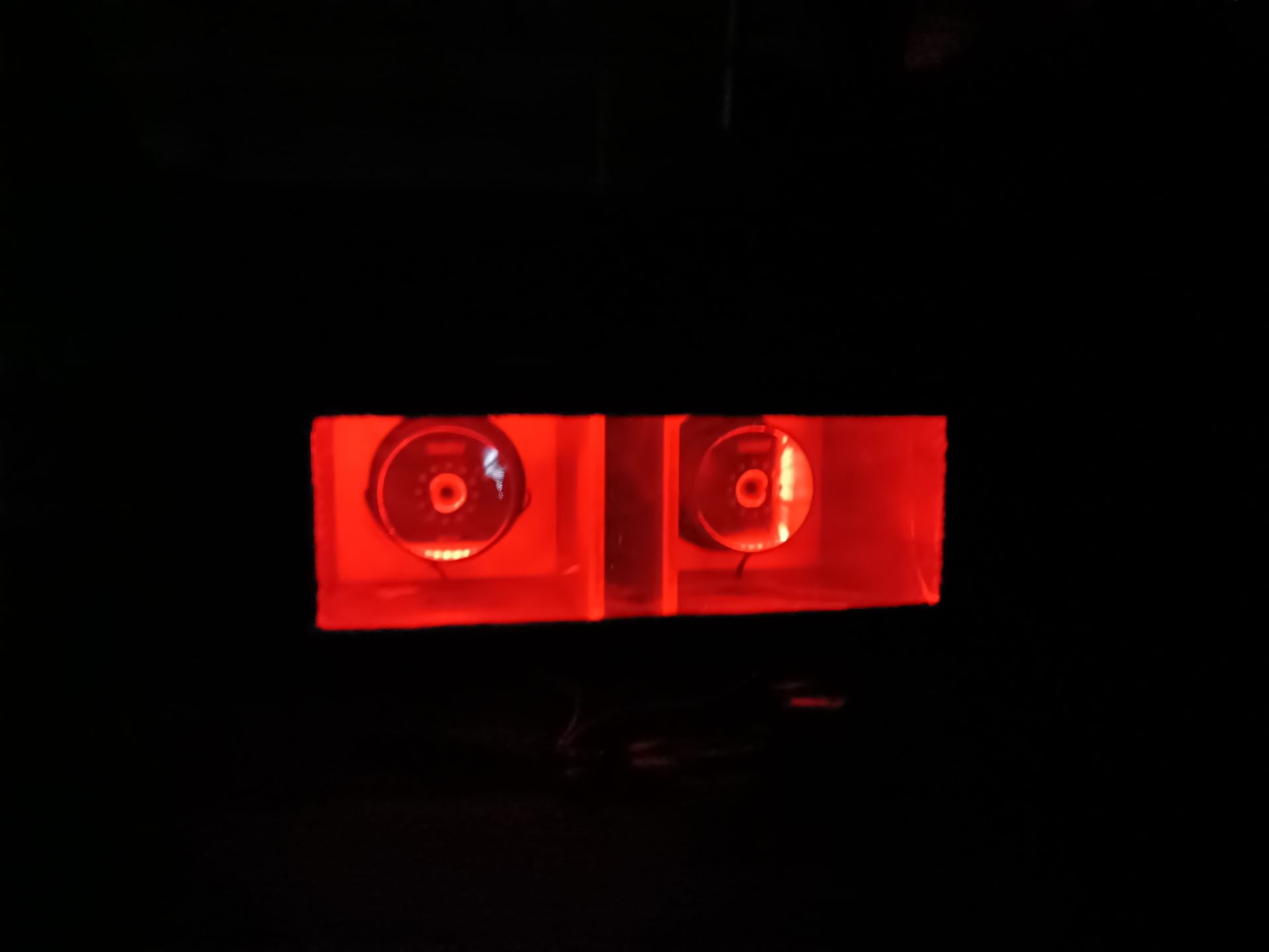 Two red glowing circular lights in a dark rectangle.