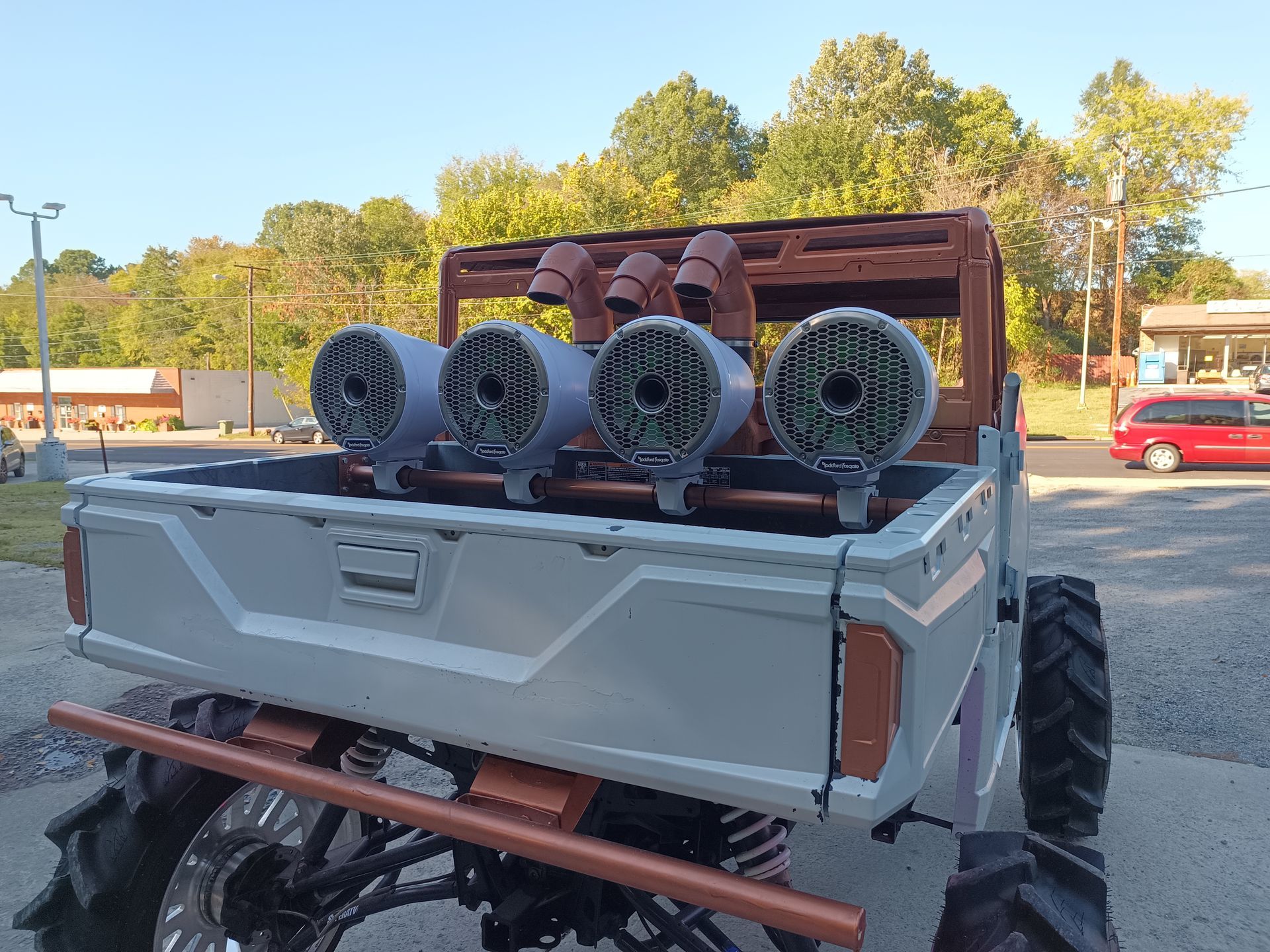 A custom mud truck with large speakers and copper accents in a parking lot.