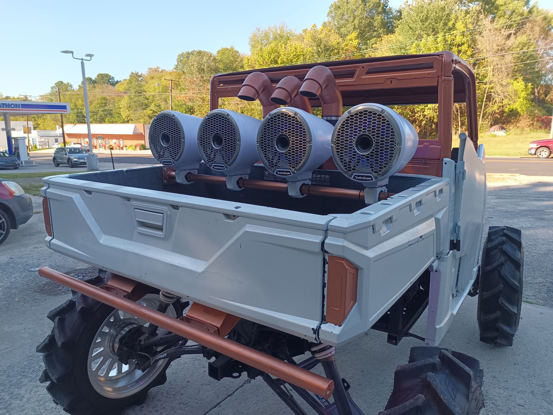 Modified all-terrain vehicle with oversized tires, speaker system, and copper accents.