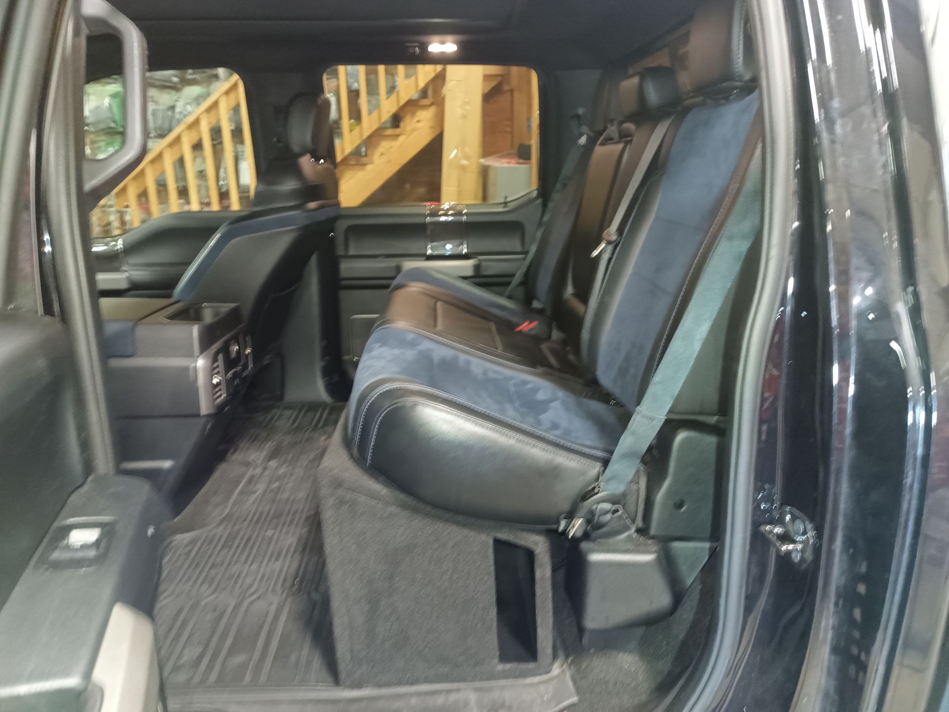 Black truck interior with rear seats, carpet, and storage compartment.