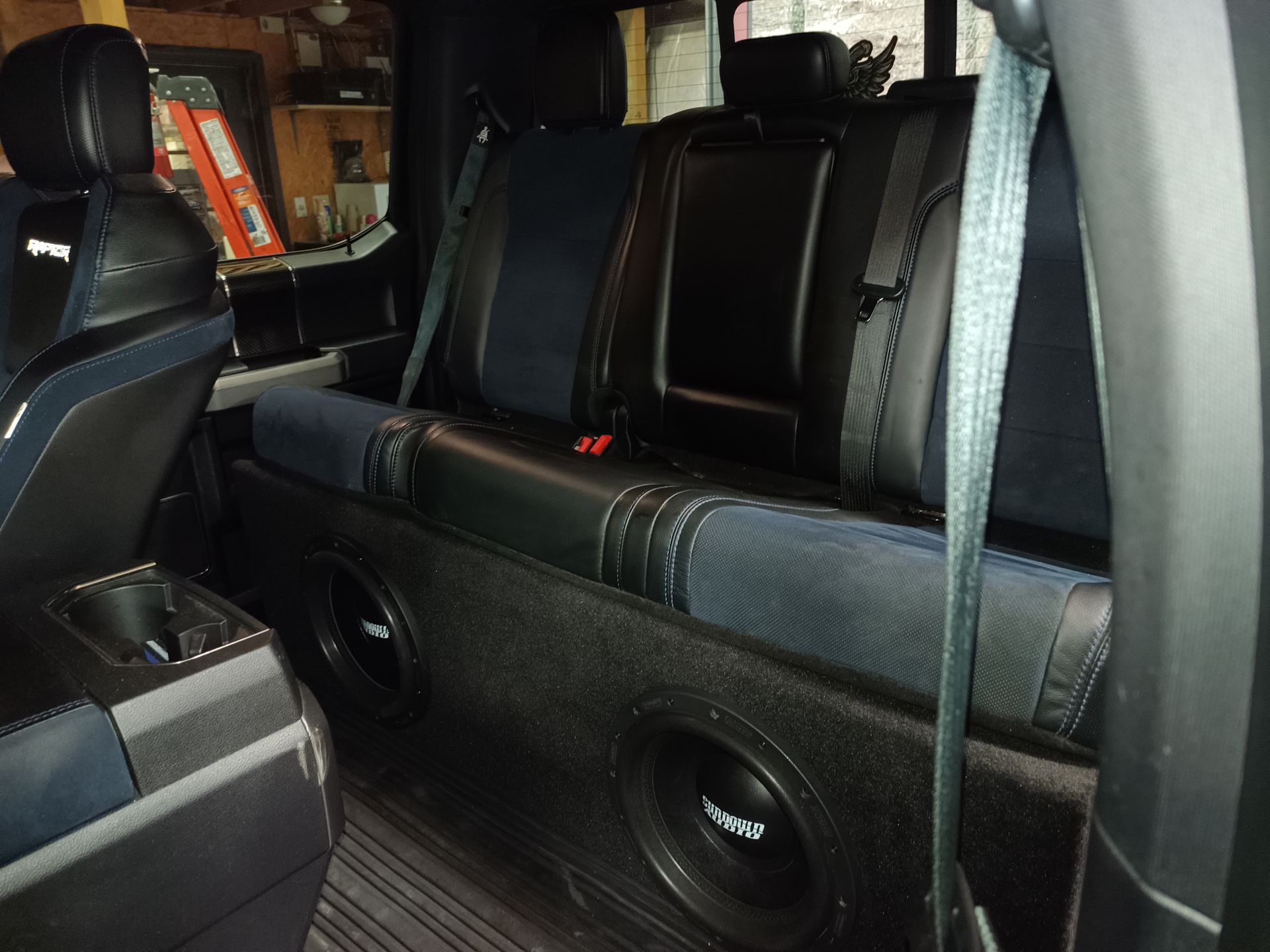 Interior view of a truck with custom subwoofer box installed below the rear seats.