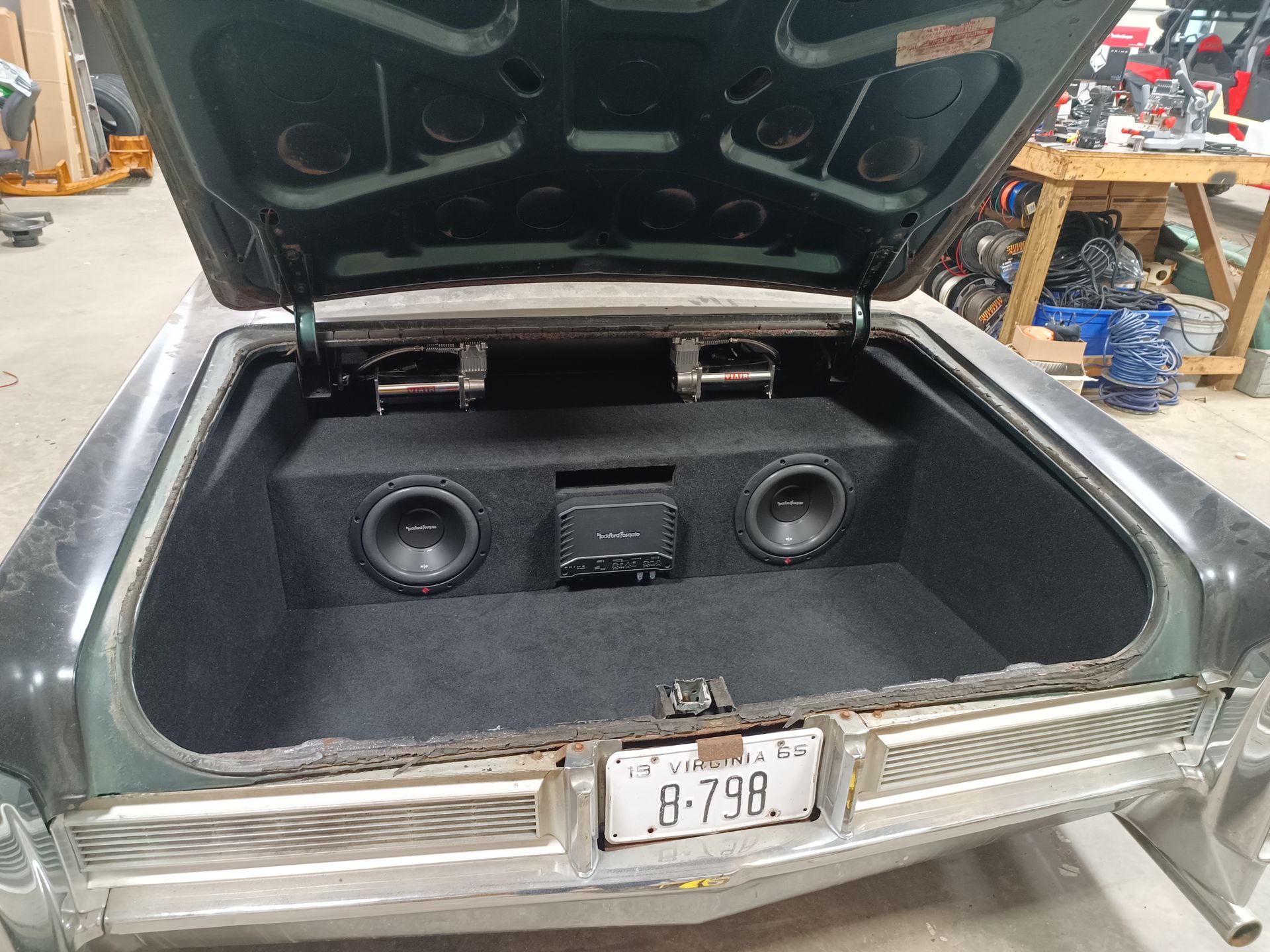 Car trunk with open lid; custom sound system installation; black box with speakers and stereo.