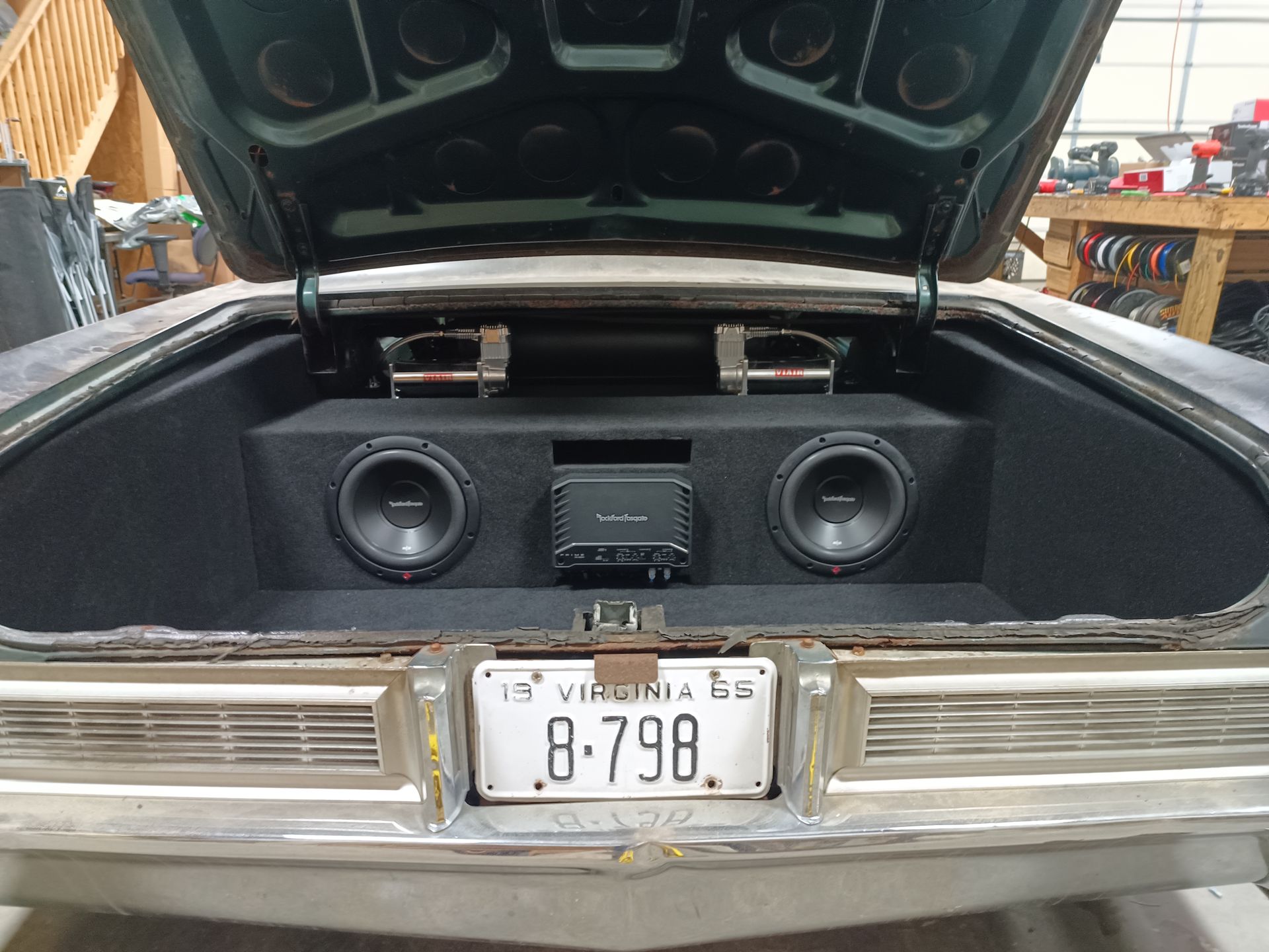 Car trunk with custom audio setup: subwoofers, amplifier, and speakers installed in a black enclosure.