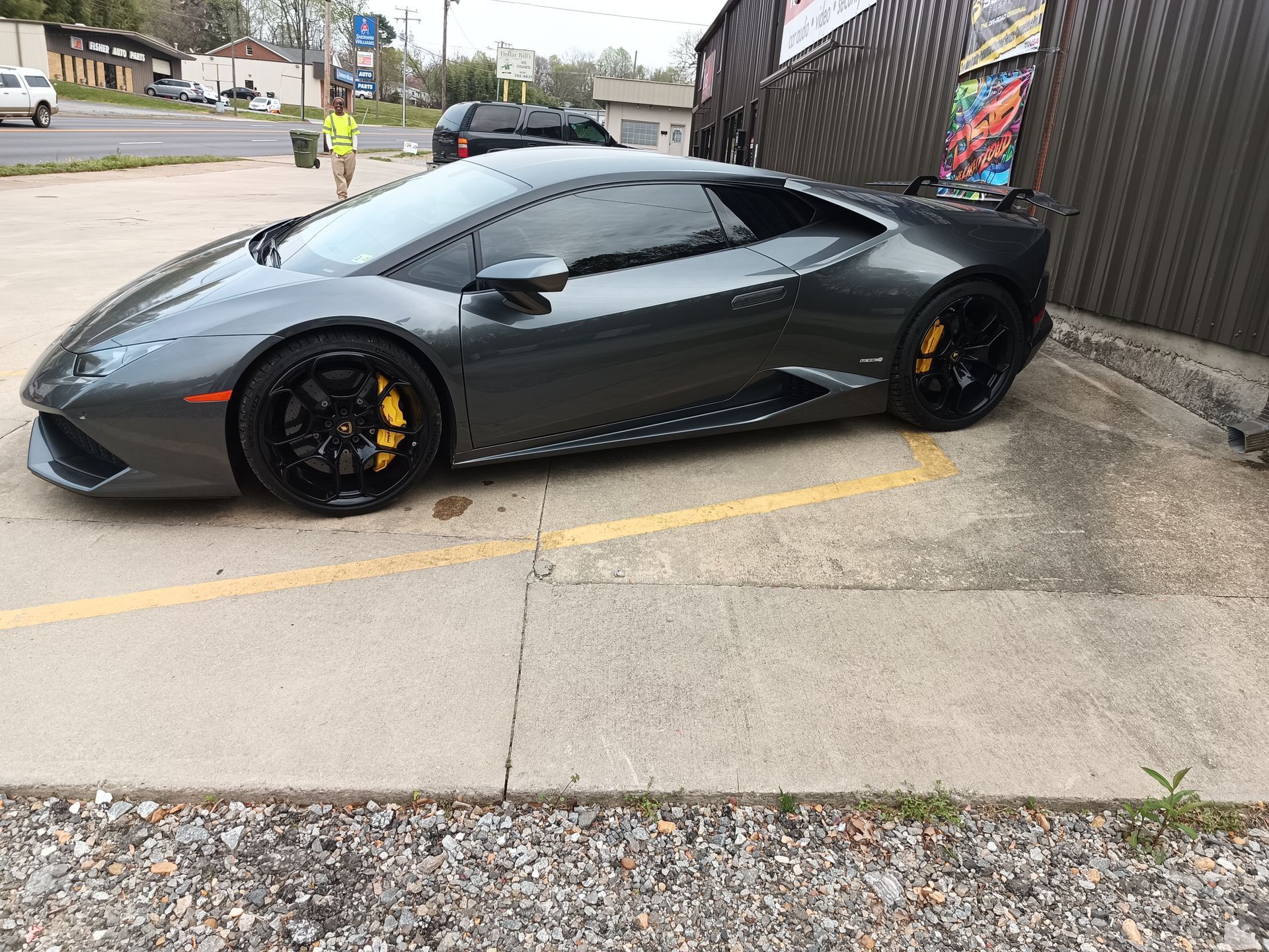 Dark gray Lamborghini with yellow brake calipers parked near a building.