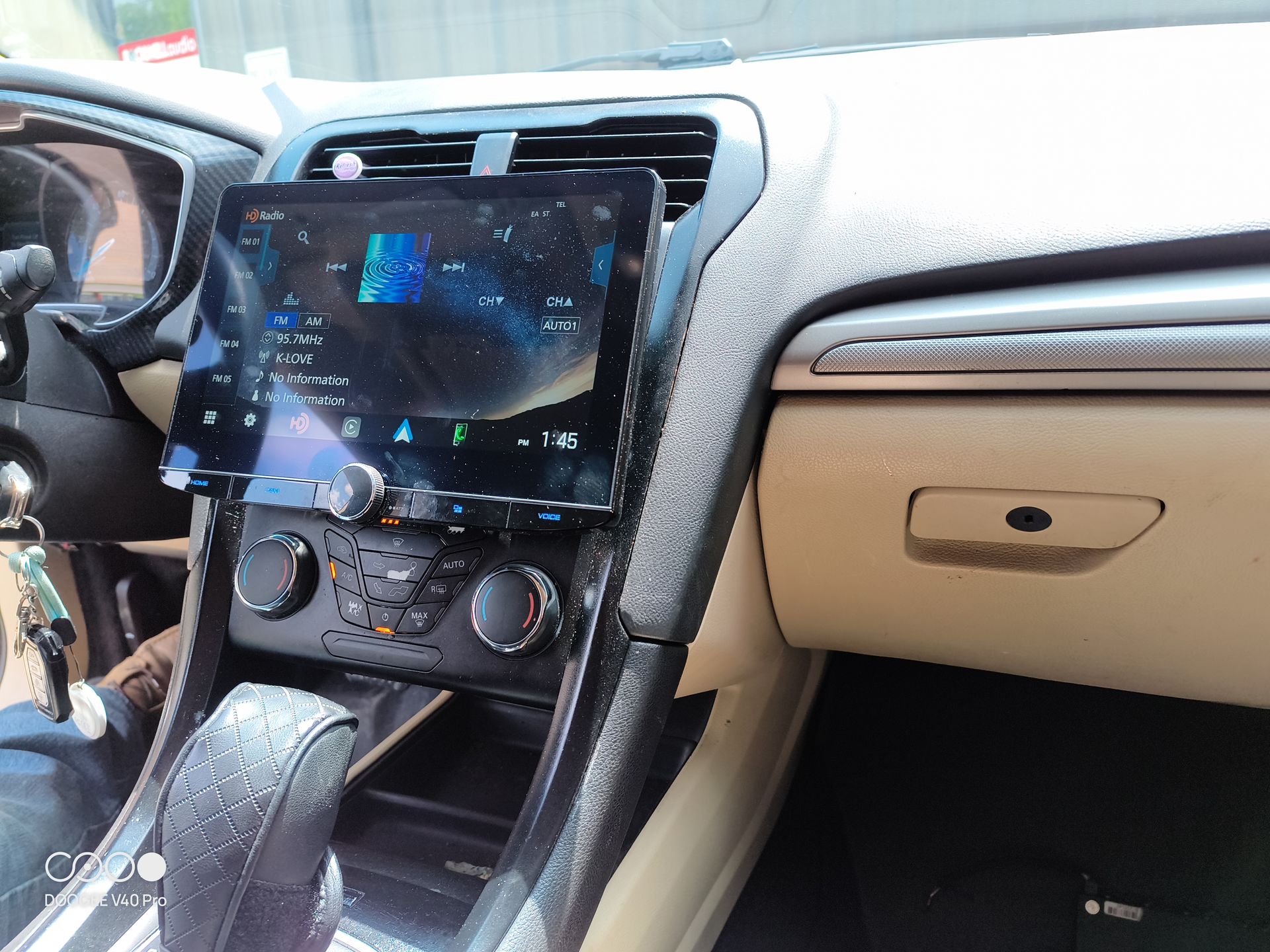 Car interior with large touchscreen display on dashboard. Beige and black details.