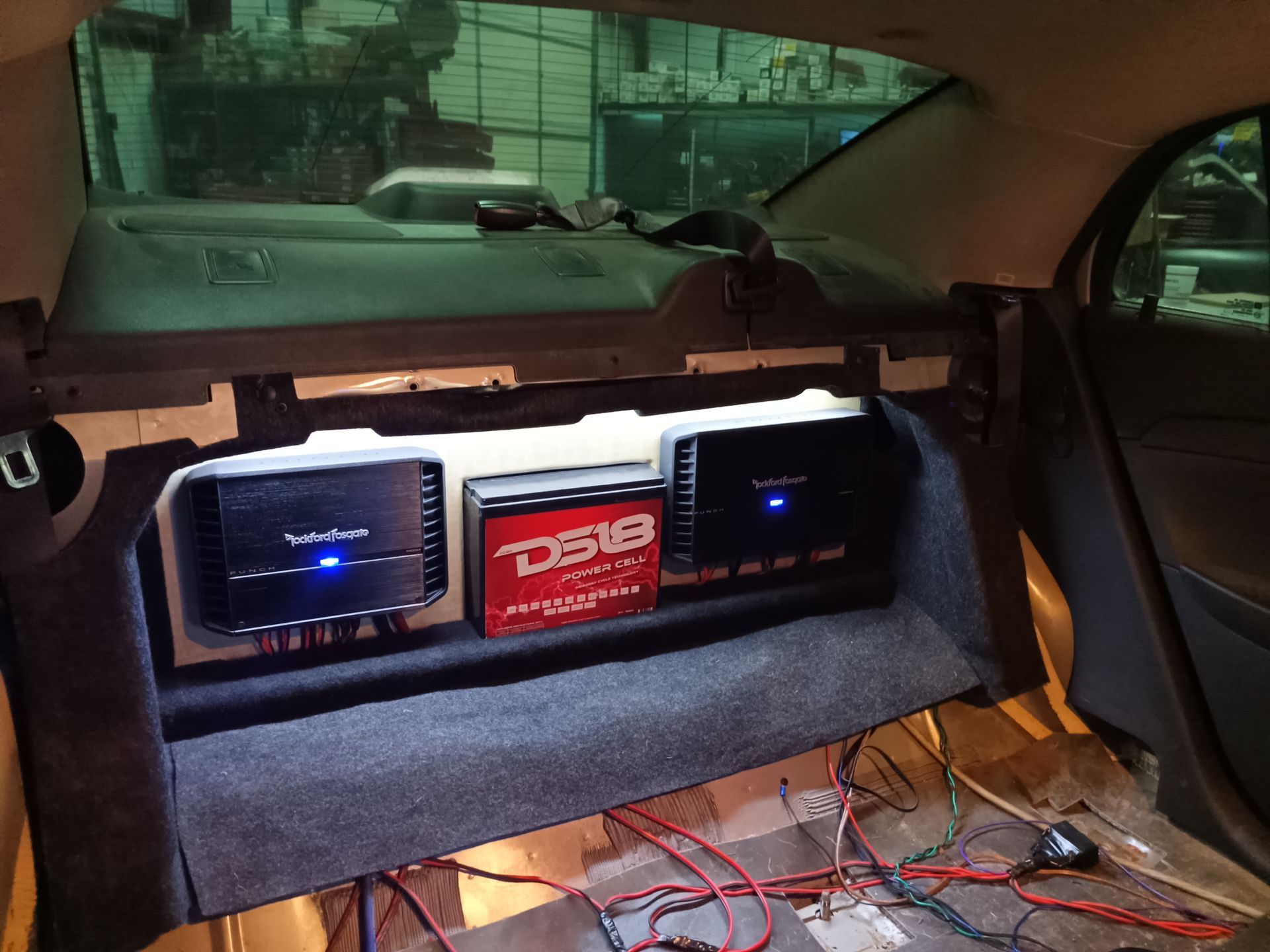 Car audio system installation, featuring amplifiers mounted in the vehicle's trunk area.