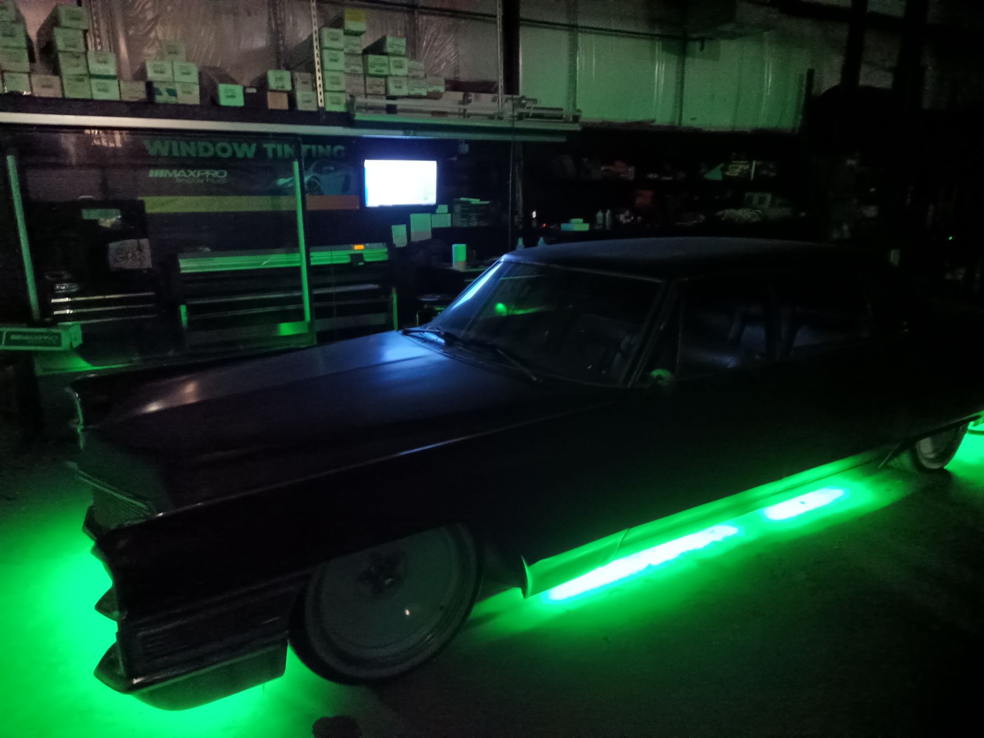 Black car with green underglow lights in a garage; a 