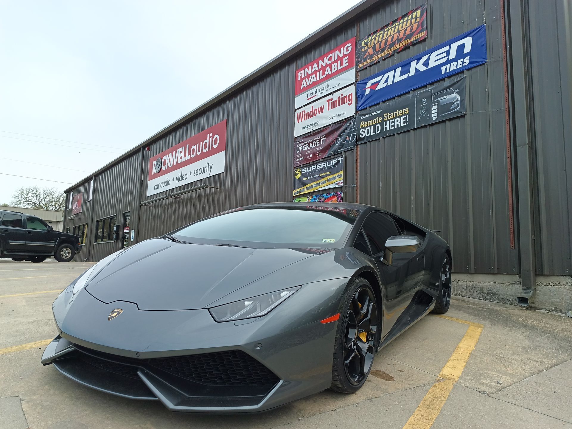 Gray Lamborghini parked in front of a building with Falken Tires sign.