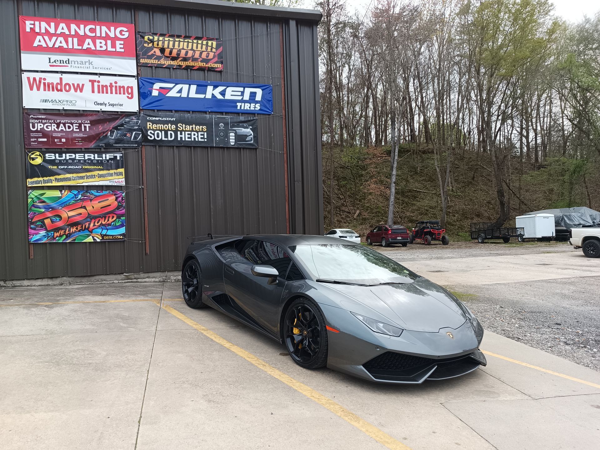 Gray Lamborghini parked outside a building with advertising signs.
