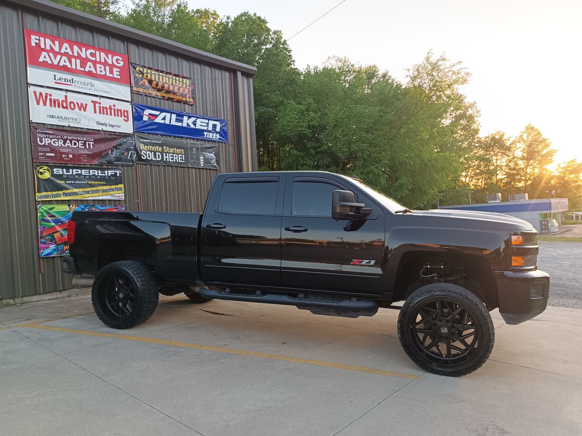 Black lifted truck parked in front of a building with advertisements.