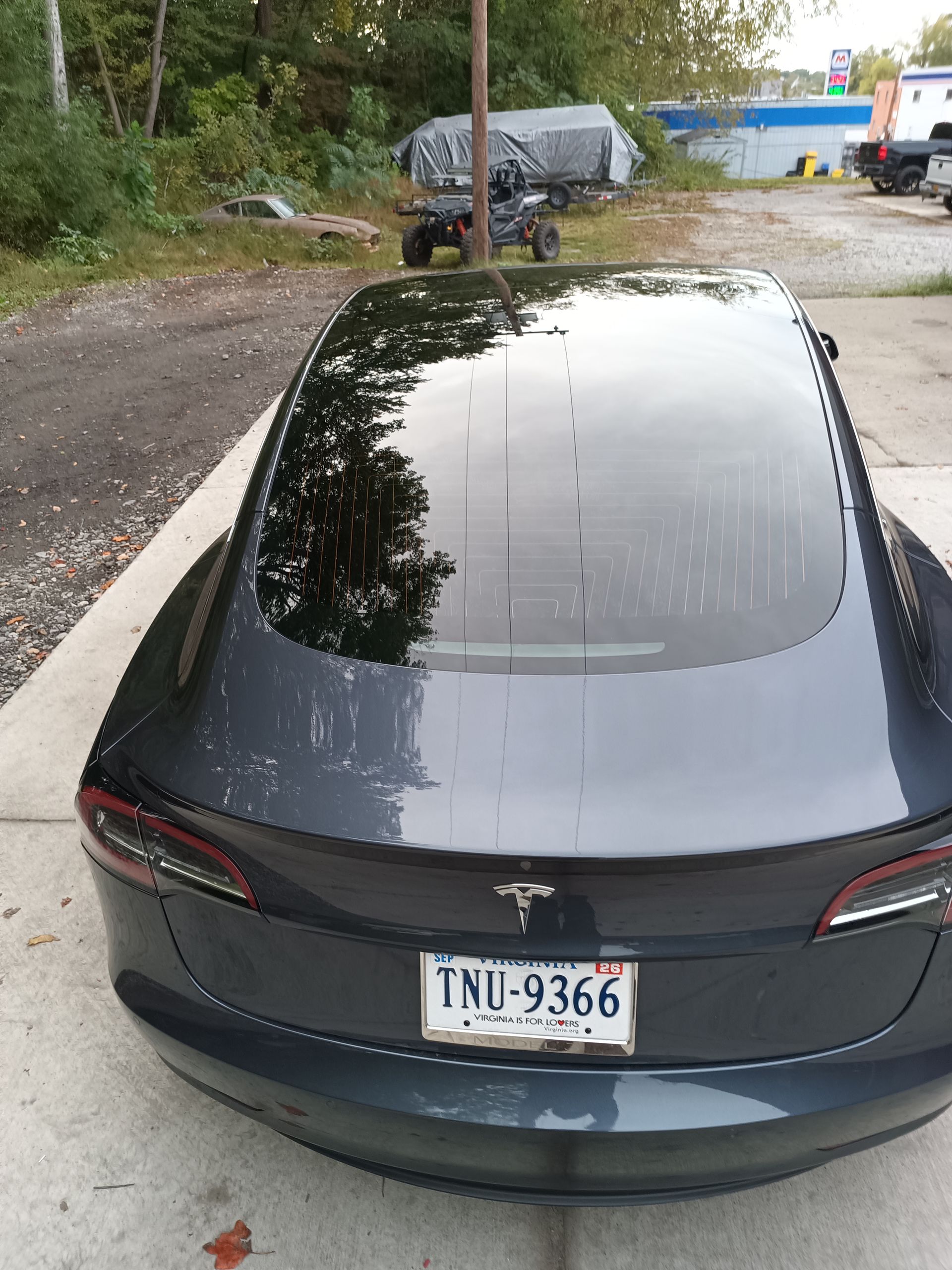 Dark gray Tesla sedan parked outdoors with license plate TNU-9366.