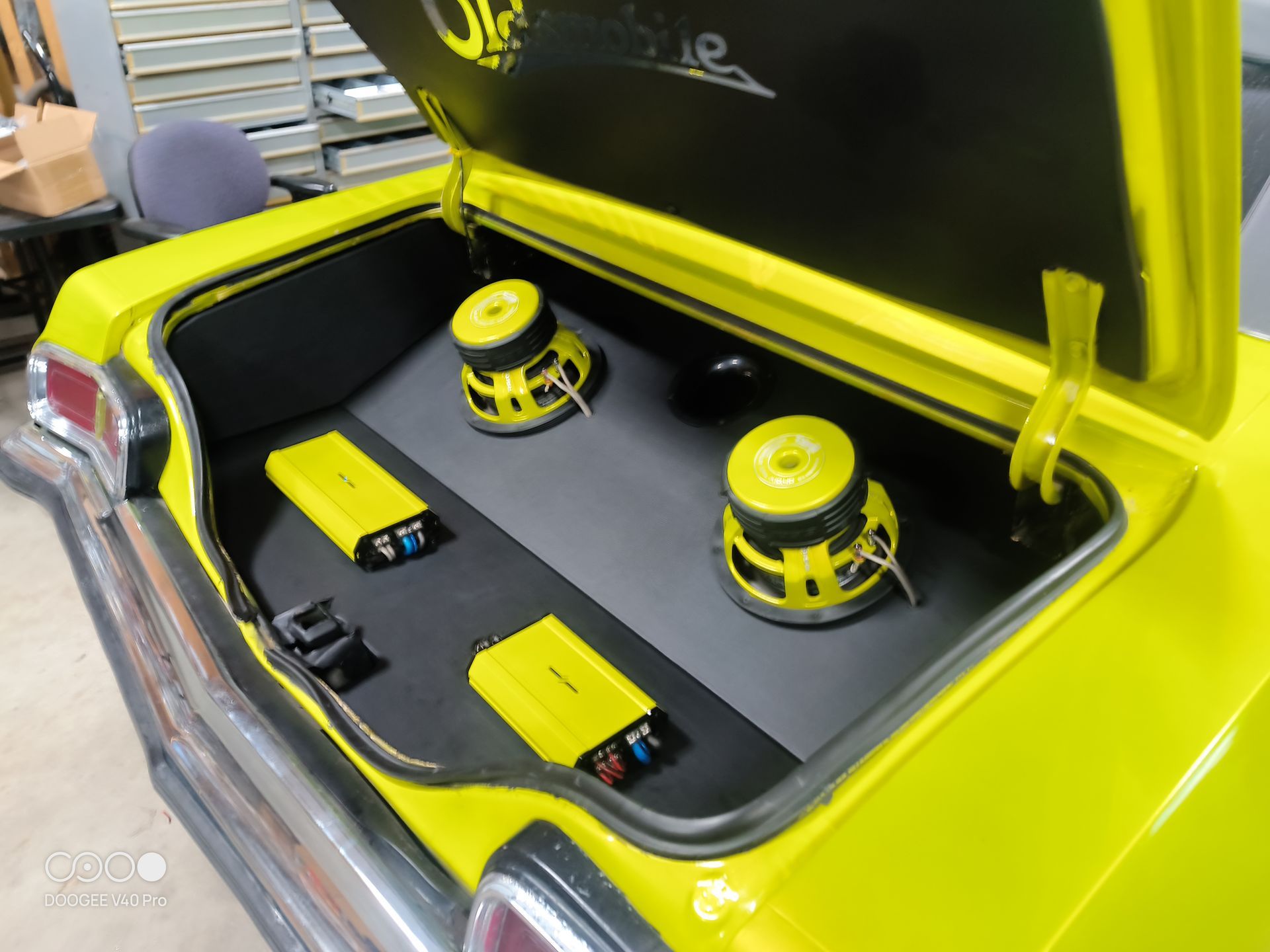 Yellow car trunk with audio system, including yellow speakers and amplifiers.
