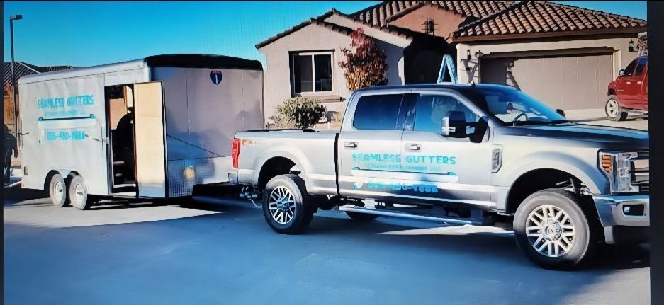 A silver pickup truck towing a trailer with open door parked in front of a house.