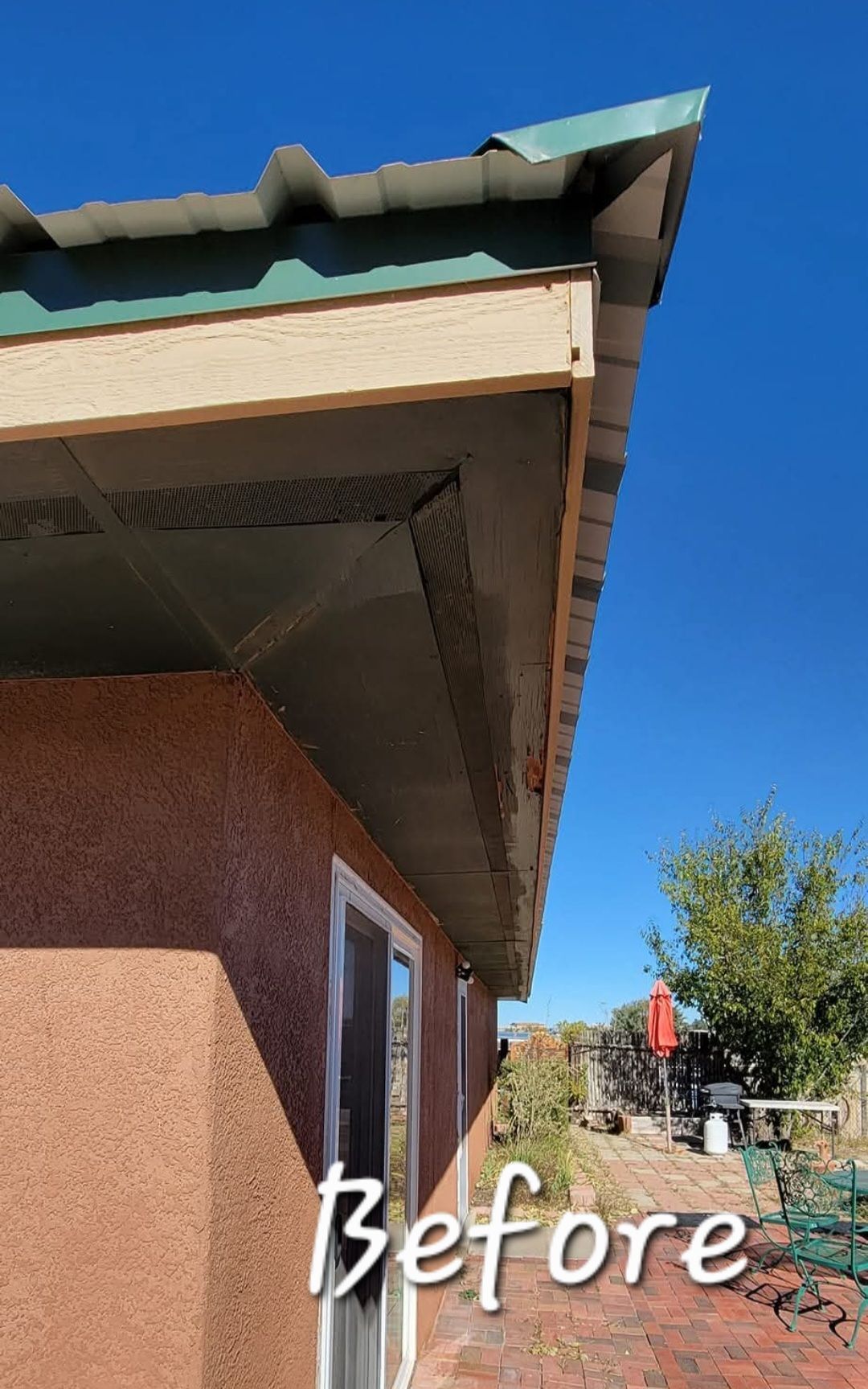 Exterior corner of a building with a green metal roof and stucco walls, labeled Before.