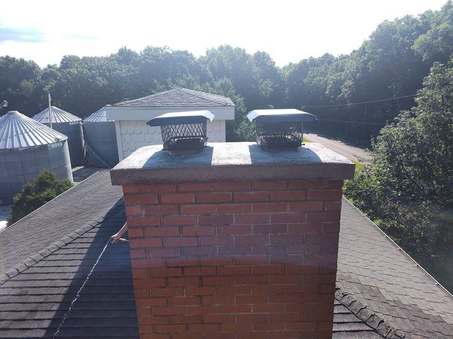 A two-story beige house with a snowy roof under a clear blue sky.