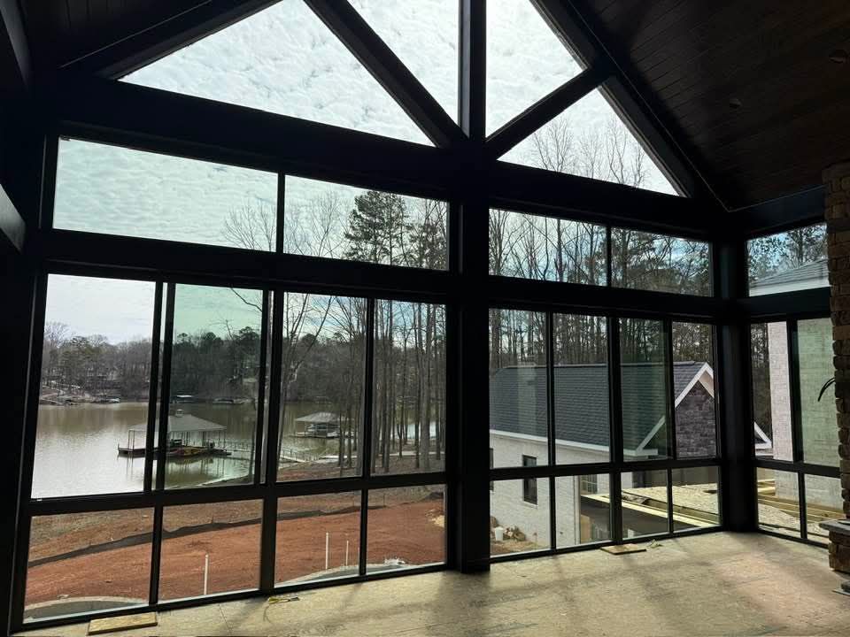 A room with a lot of windows and a view of a lake.