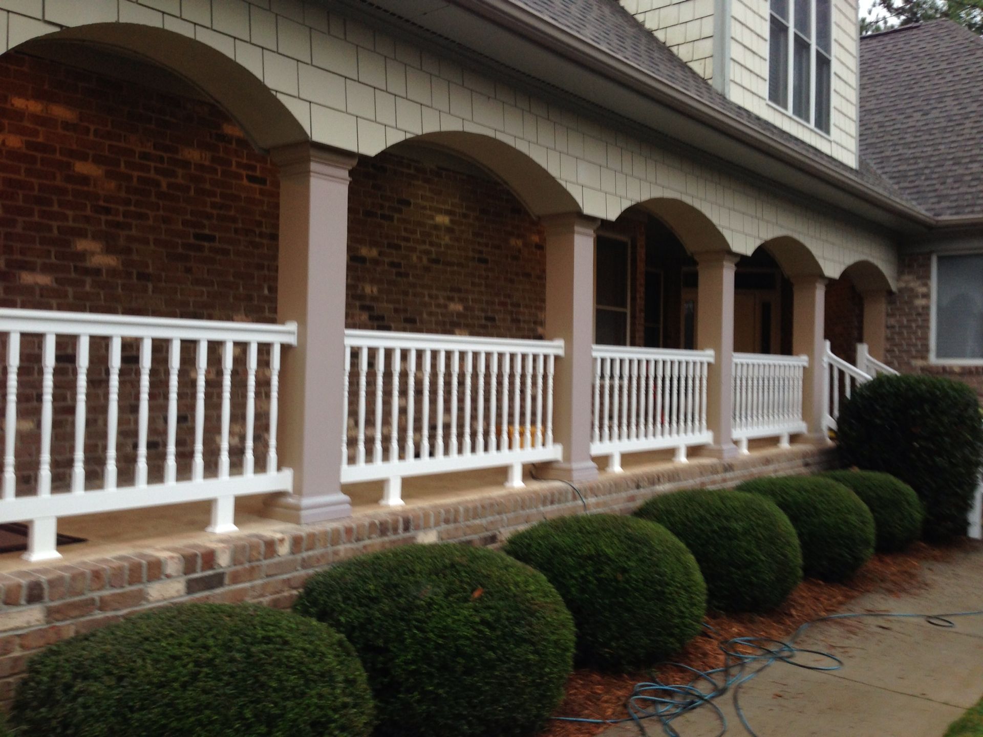 A brick house with a white railing on the porch