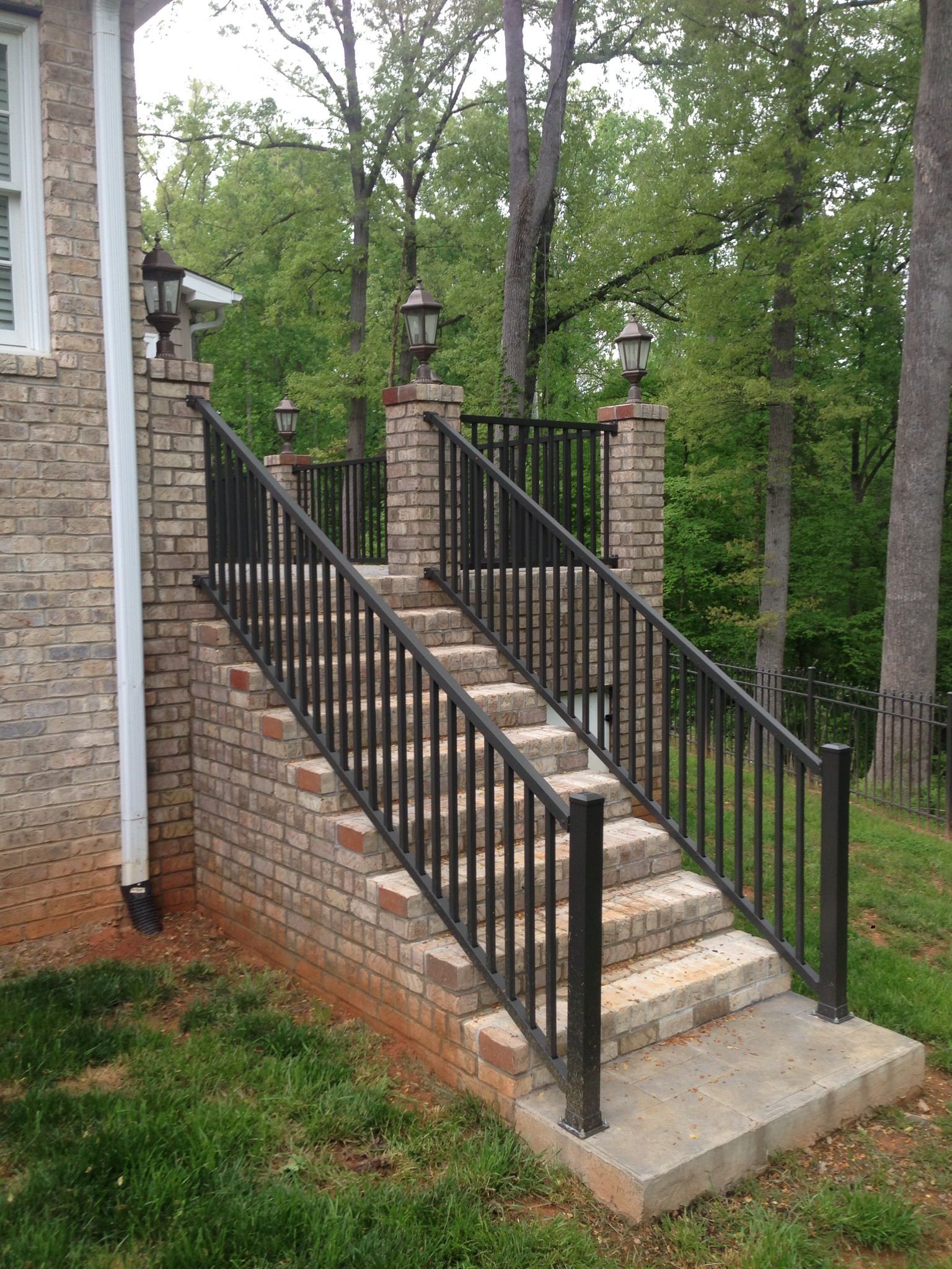 A set of stairs leading up to a brick house with a metal railing.