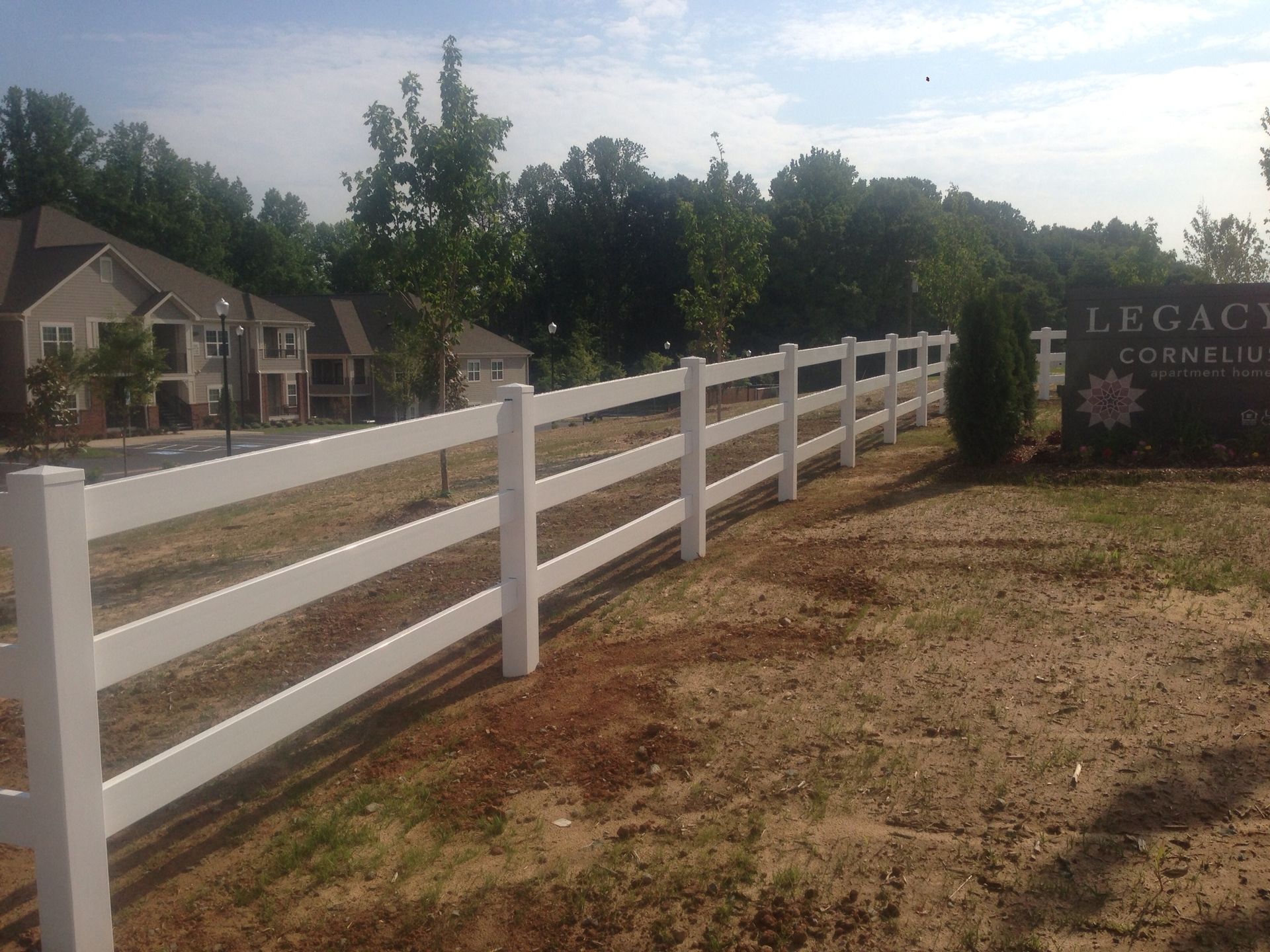 A white fence surrounds a sign for legacy apartments.