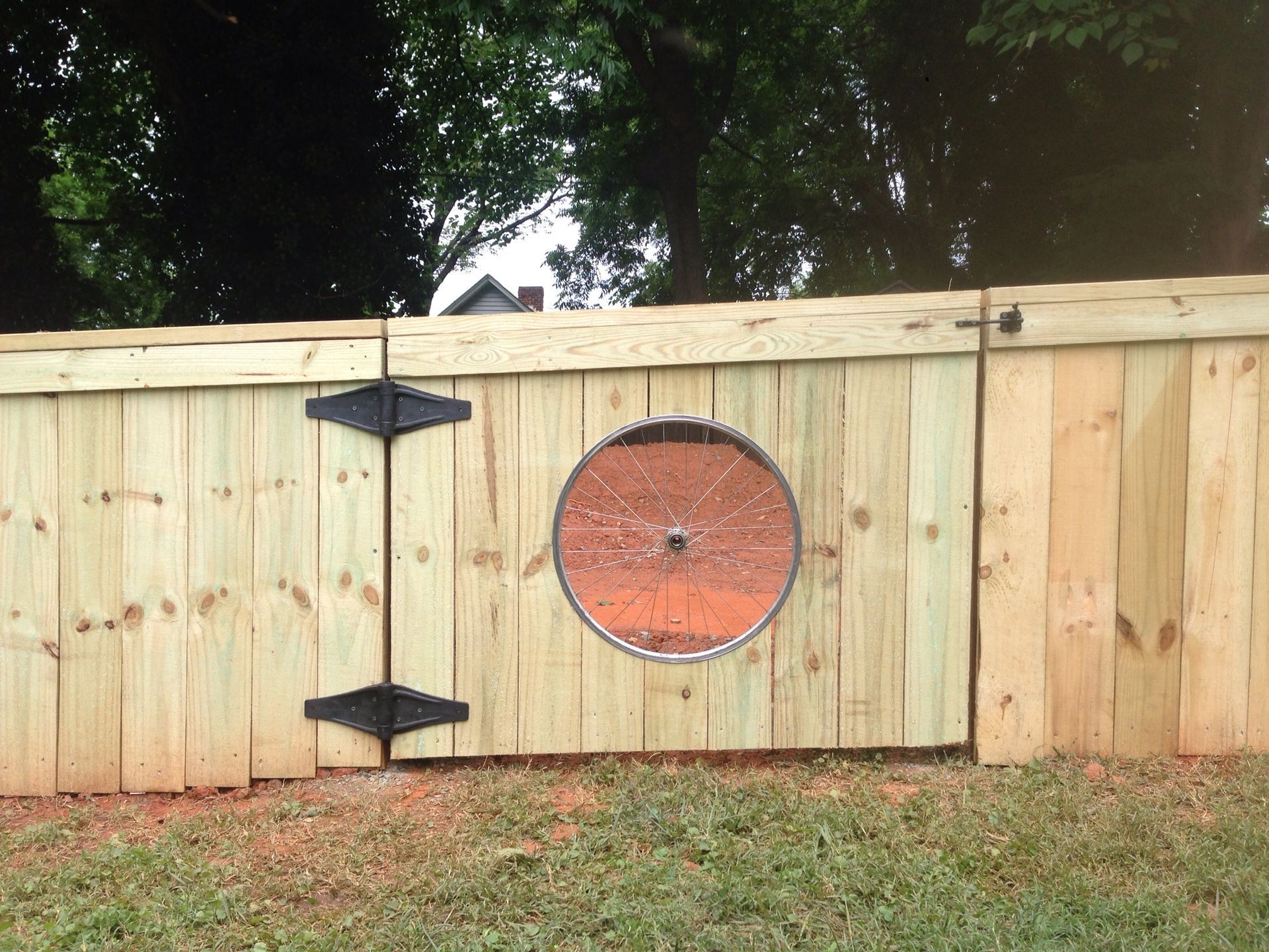 A wooden fence with a bicycle wheel in the middle of it.