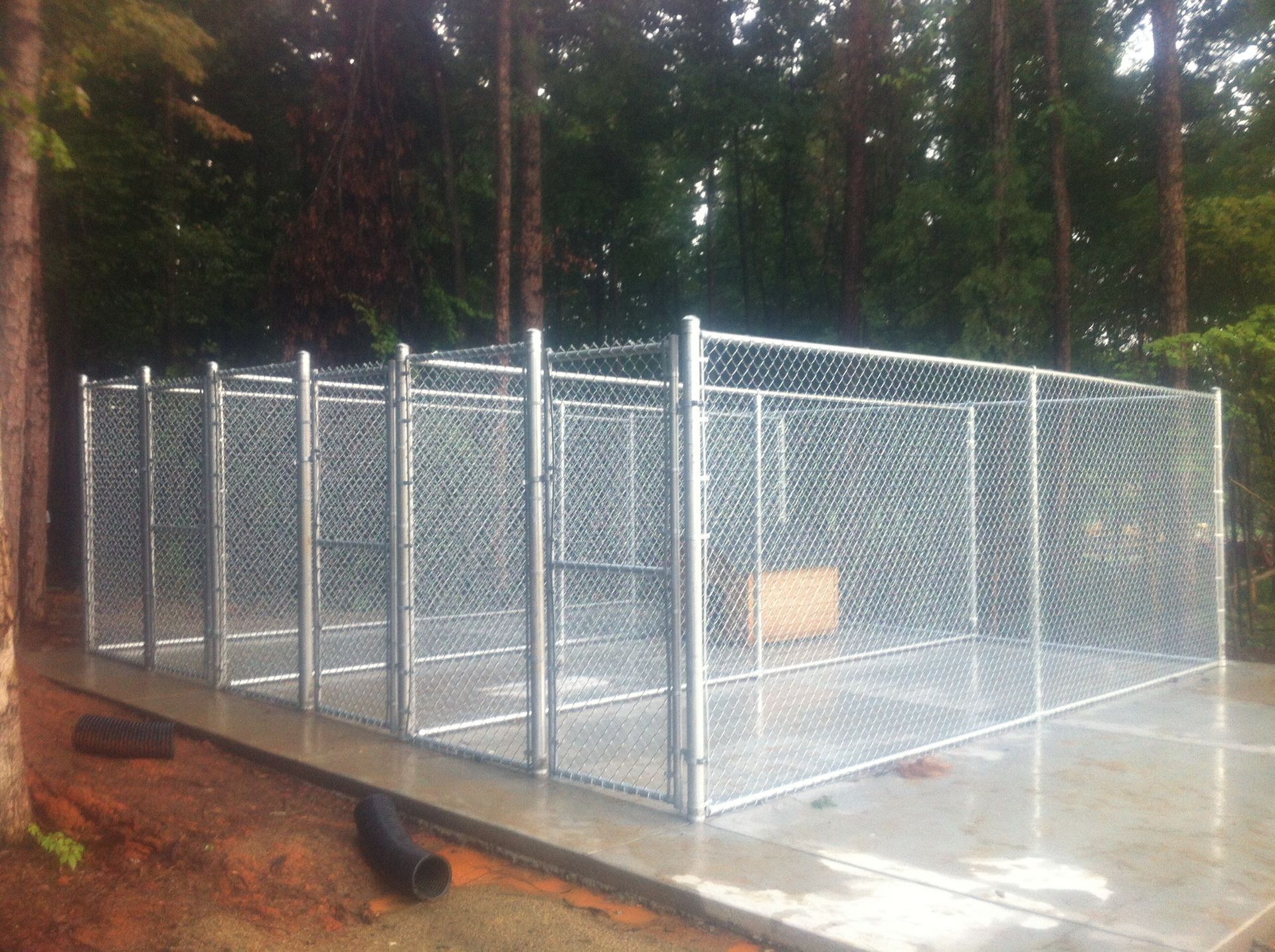 A large chain link fence is sitting on top of a concrete floor.