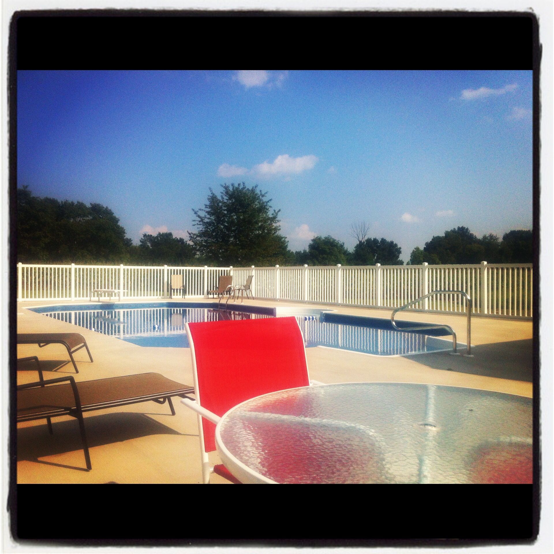 A swimming pool with chairs and a table in front of it