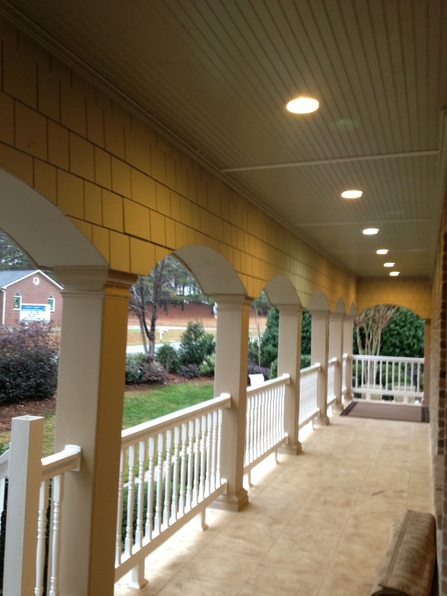 A porch with a brick wall and white railing